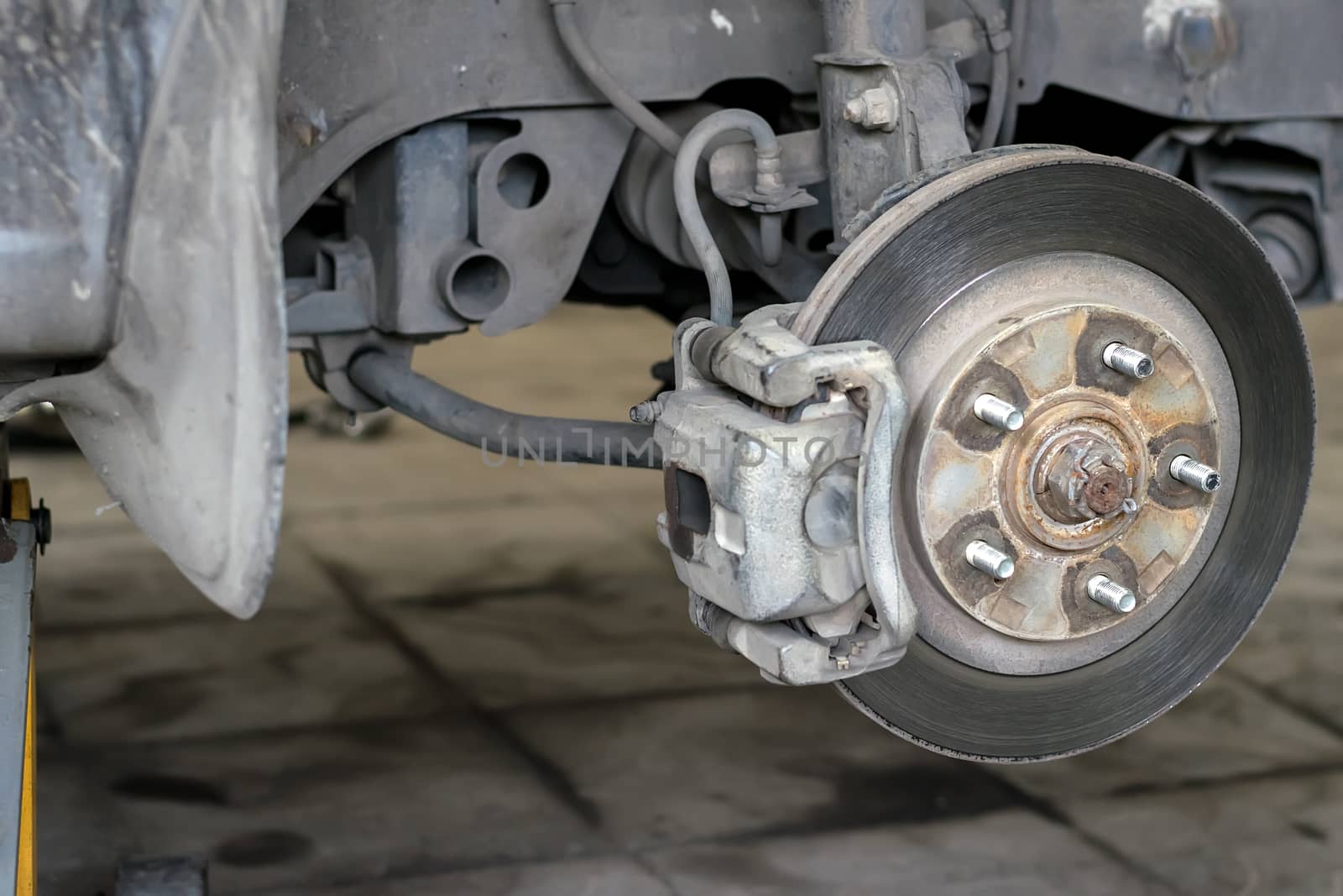 Wheel arch of the car with the removed wheel. Brake disc car wheels with caliper at the service station close-up