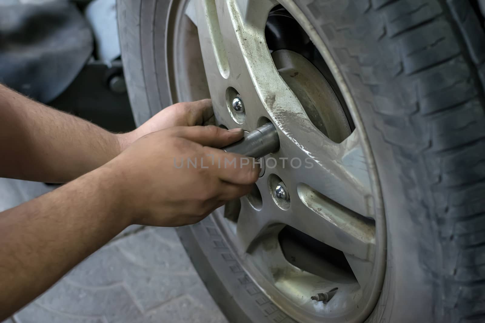 Human hands screw nuts in the wheel of the car by jk3030