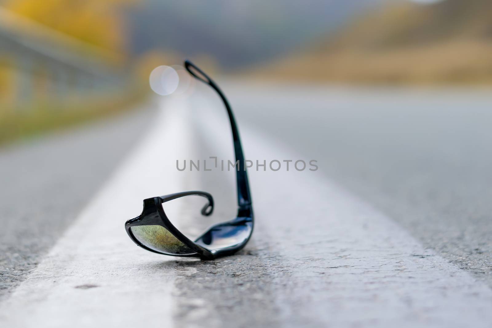 close up, lost sunglasses lie on the road asphalt on a country track on the dividing strip at the curb
