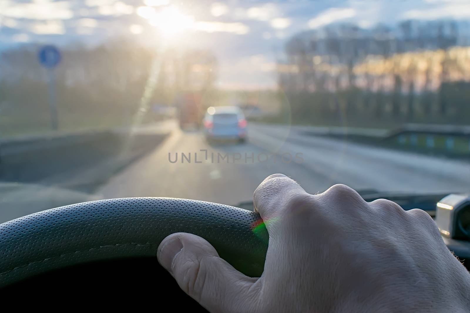hand of a man on the steering wheel of a car by jk3030