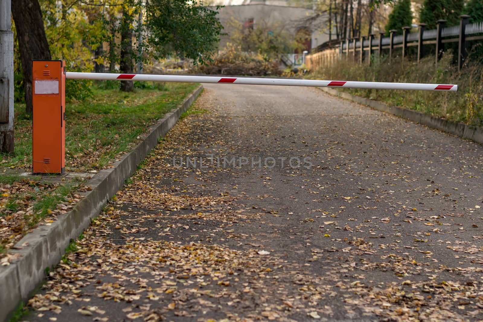 the barrier on the road leading to the building on the background of fallen autumn leaves