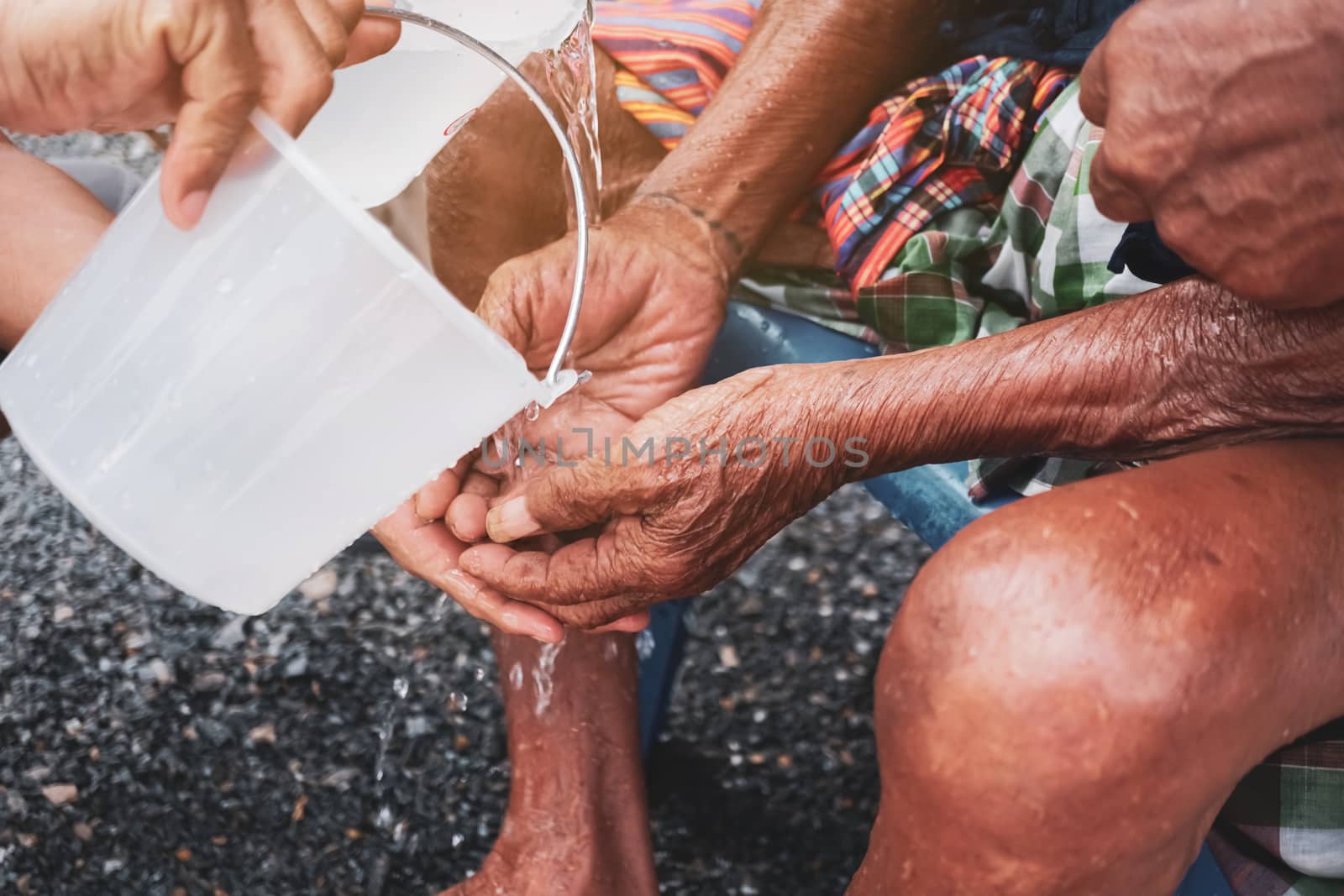 Person pour water on the hands of elder in family for doing respected and ask for blessing in Thai Songkran festival.  by Suwant