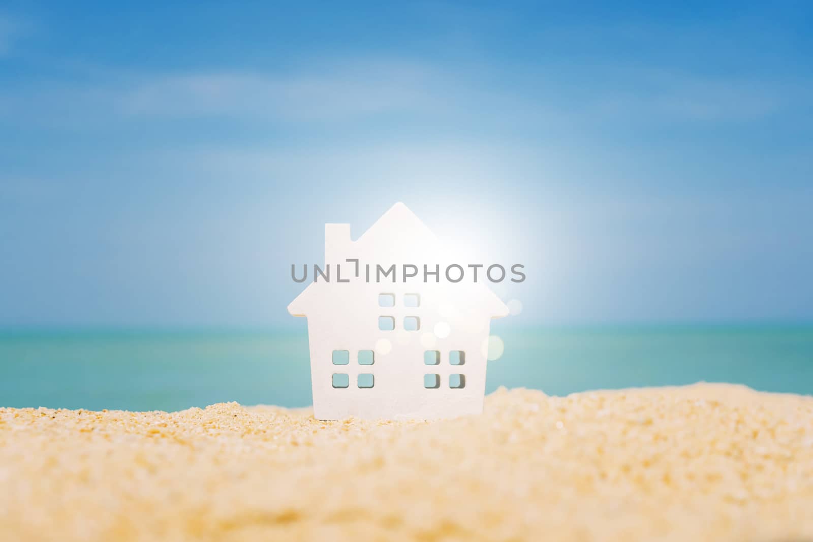 Model of a little house on sand with nature beach background. Dream life concept.