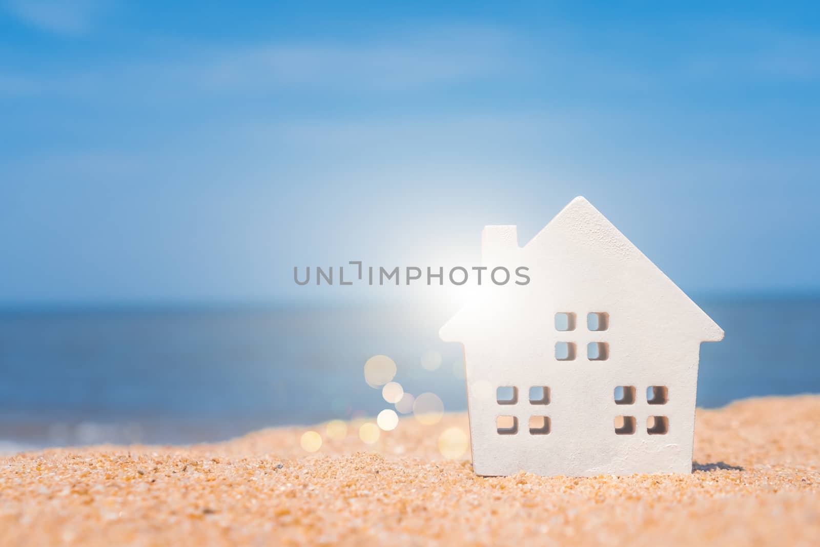 Model of a little house on sand with nature beach background. Dream life concept.