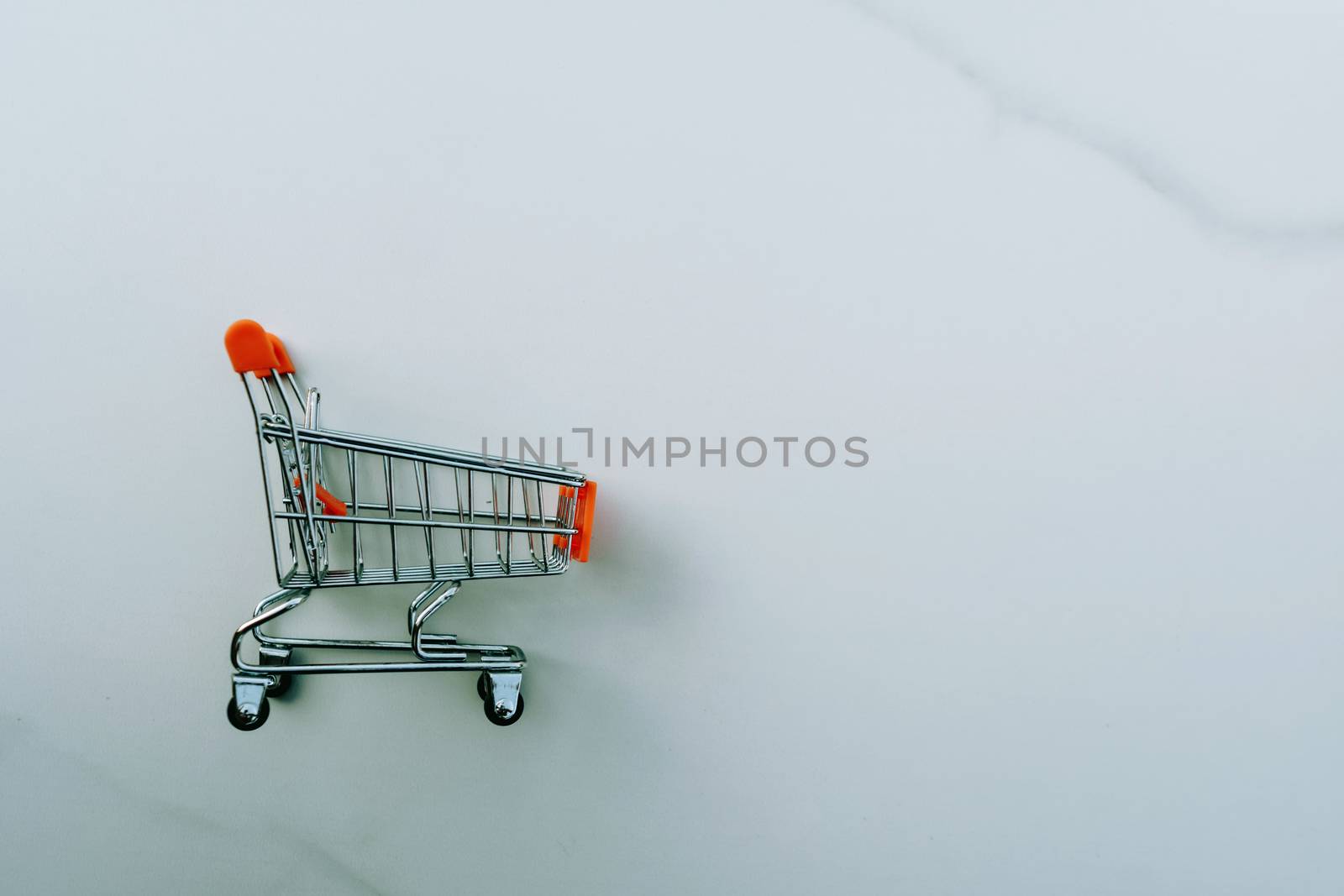 Shopping cart on marble white floor texture.