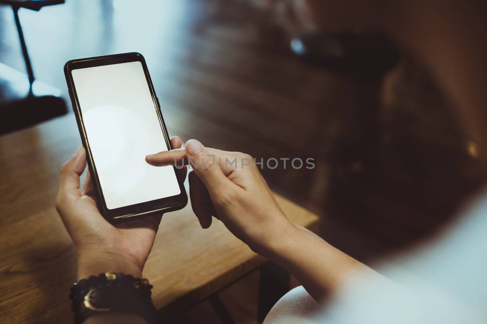 Woman hand use smartphone to do work business, social network, communication in public cafe work space area.