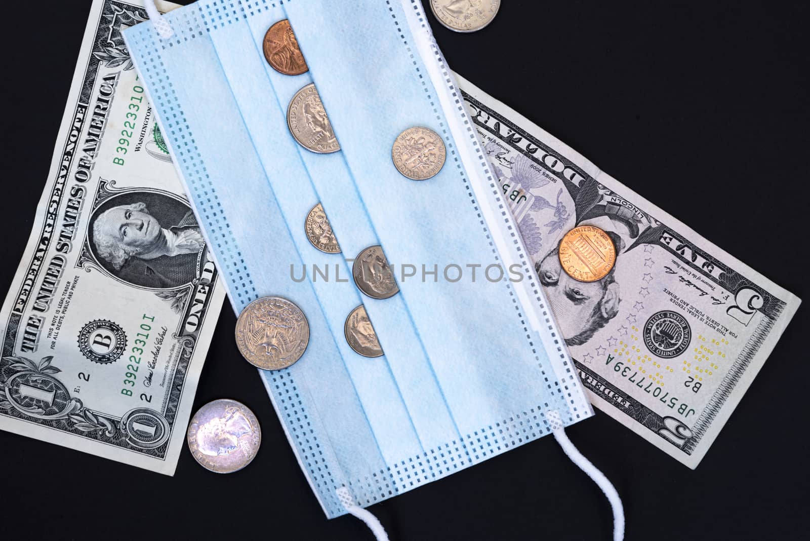 Medical face mask and money on a black background. World coronavirus epidemic and economic losses concept. Concept of financial impact of covid-19 on money United States Dollar.