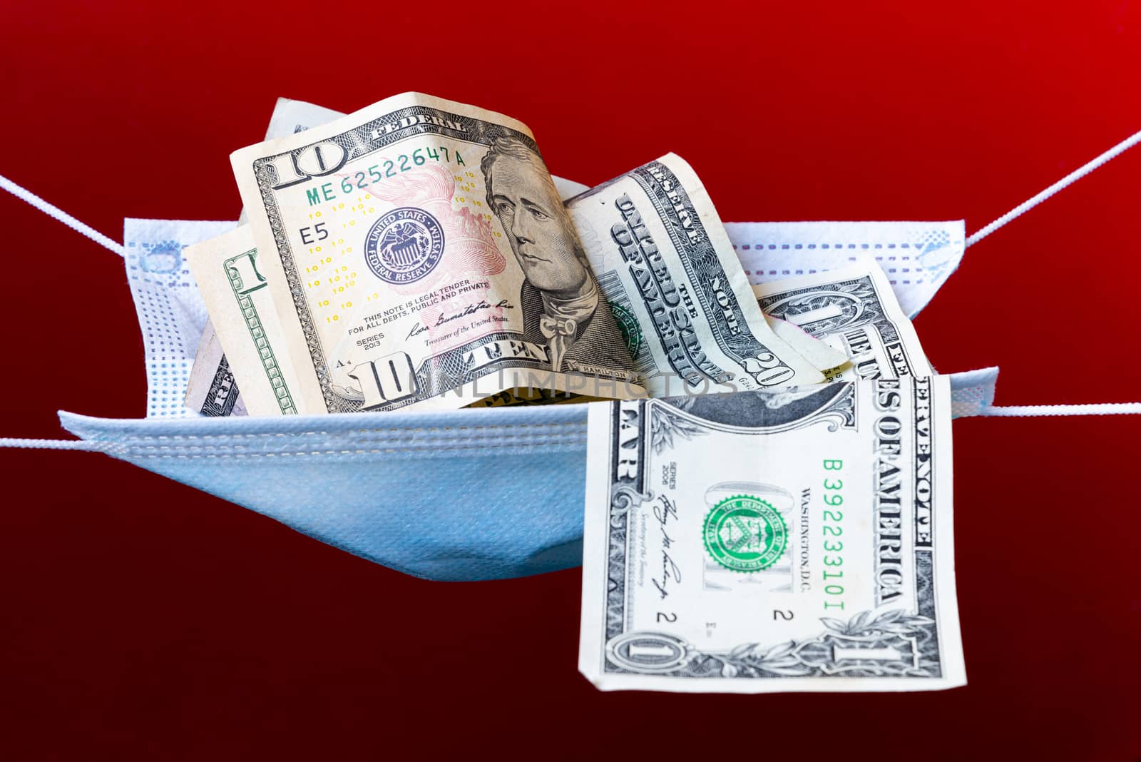 Medical face mask and money on a red background. World coronavirus epidemic and economic losses concept. Concept of financial impact of covid-19 on money United States Dollar.