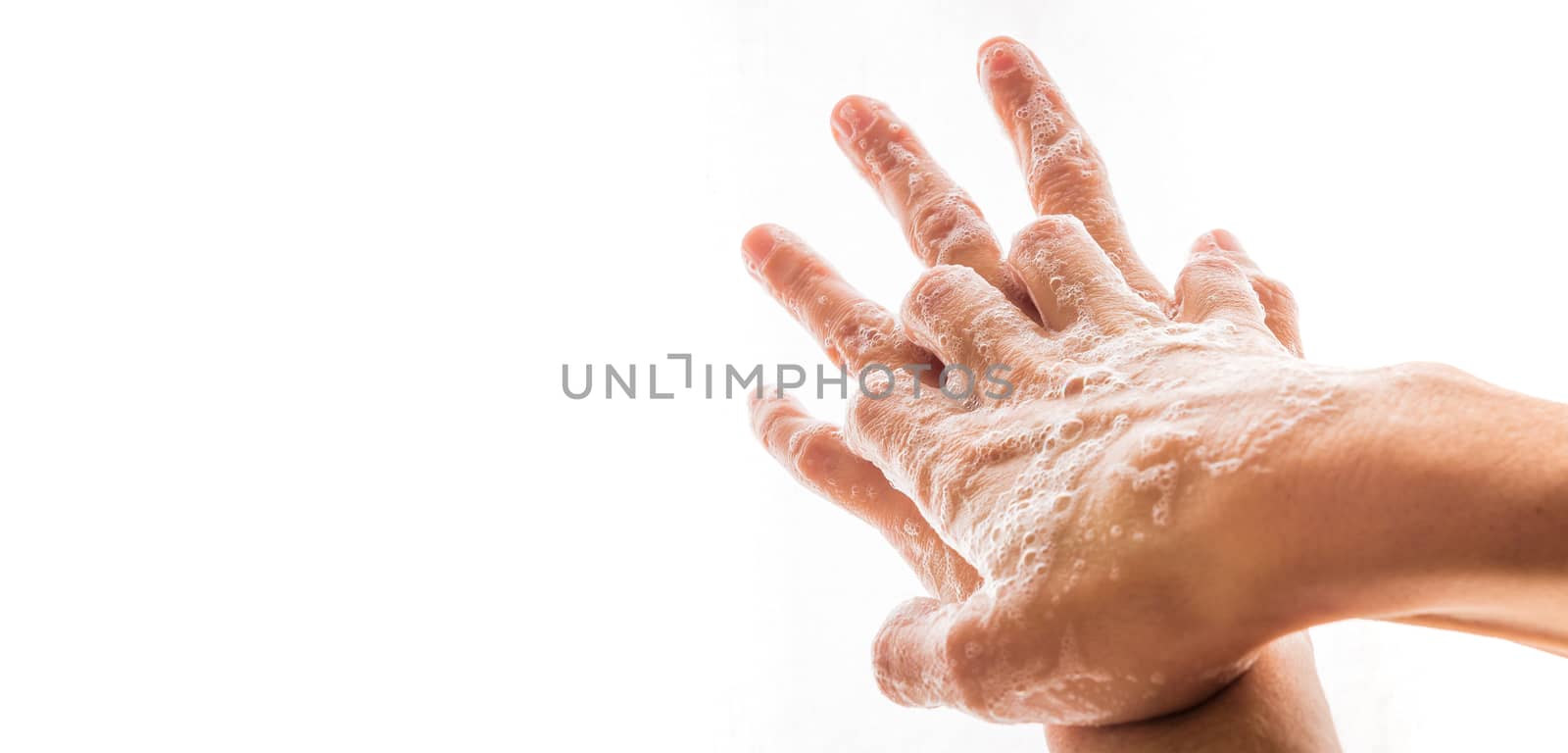 Two human hands washing with soap and bubbles.