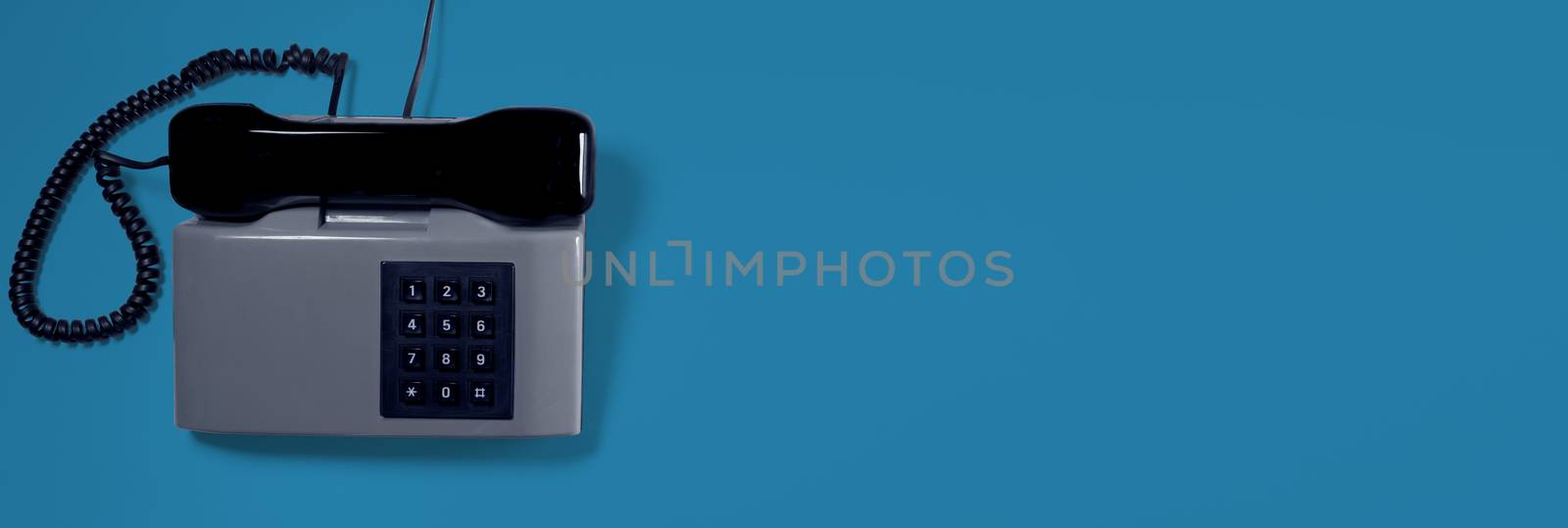 A grey vintage telephone with blue background. Business card.