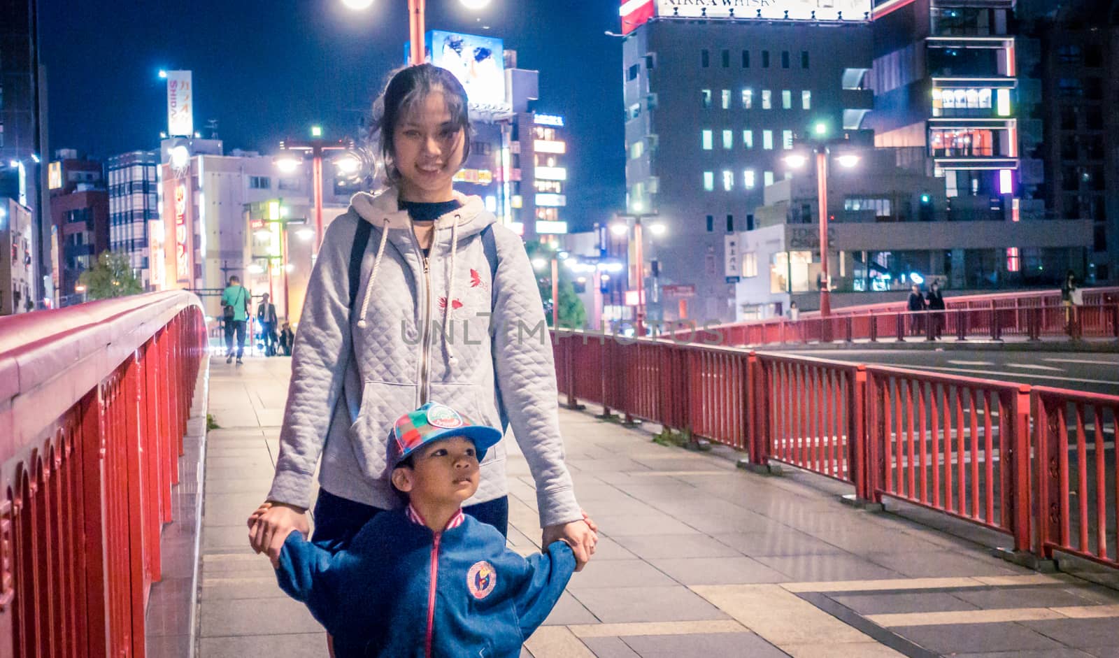 Asian Tourists is taking picture on the red bridge of Asakusa by junce