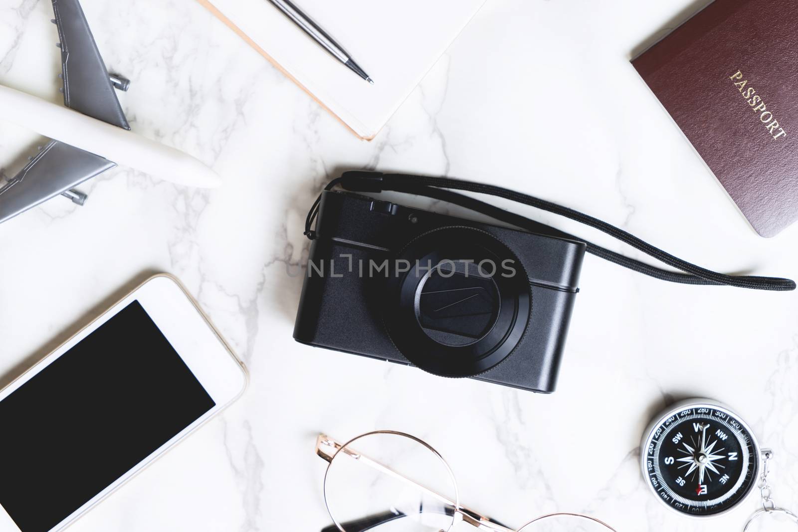 Travel accessories flatlay on marble with camera in the middle by junce