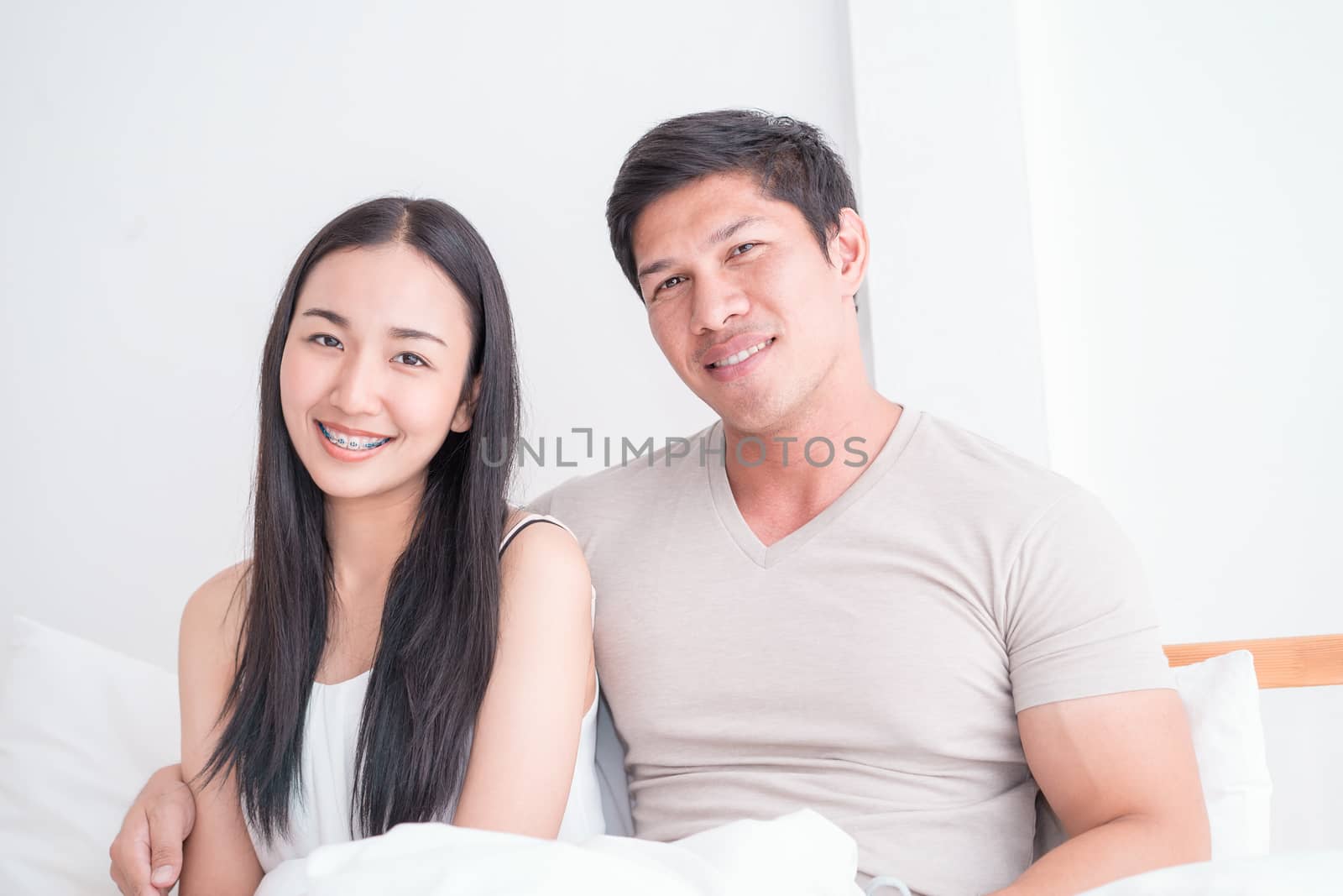 Happy Asian couple on bed with bright morning light