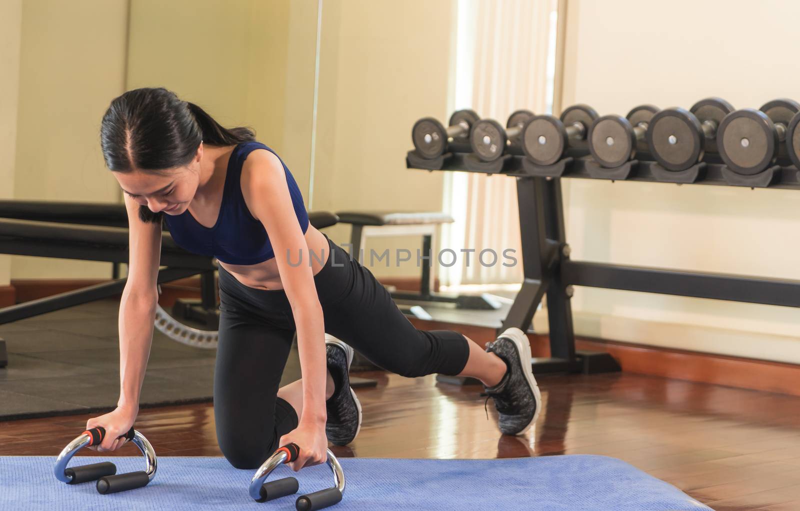 Strong asian woman is doing a plank in a fitness gym