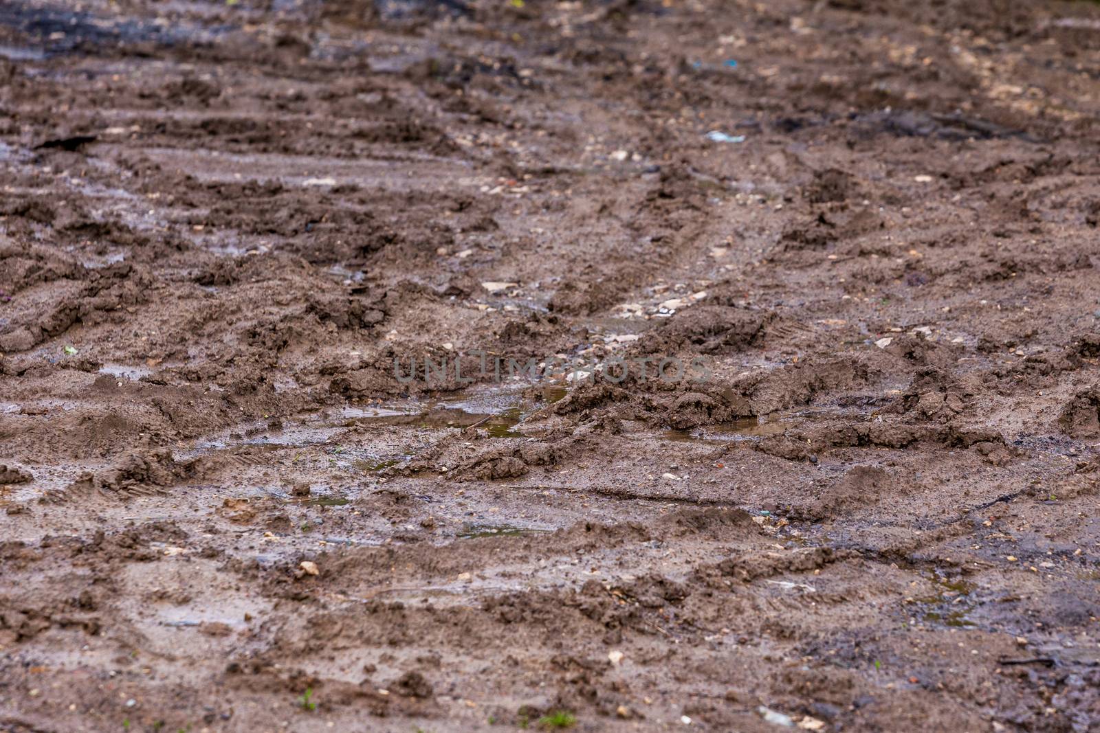 dirty clay mud road with tire tracks - closeup with selective focus and field blur