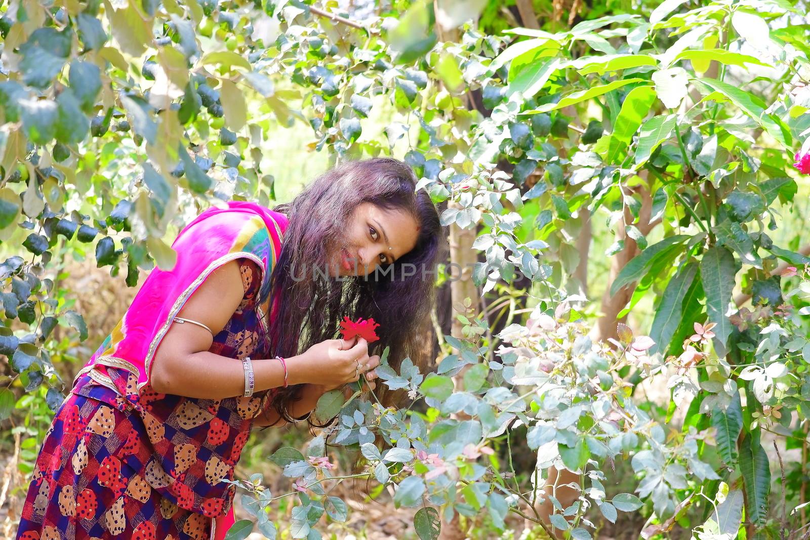 A young girl holding a red rose flower in open hair and looking at the camera