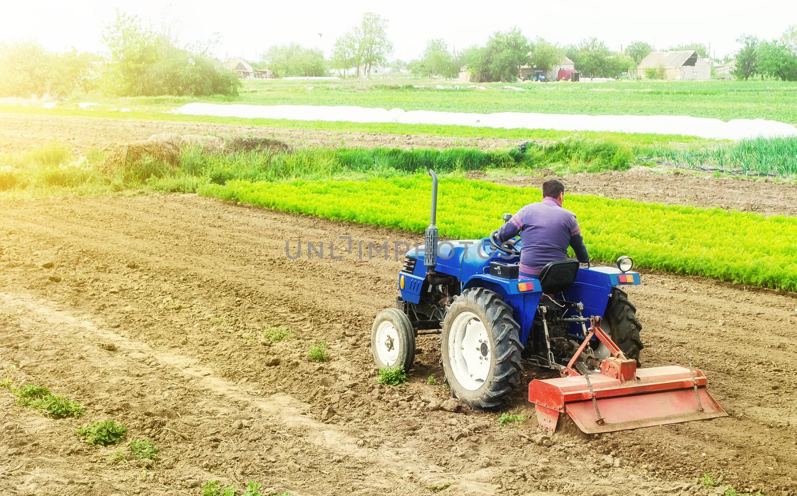 Farmer on a tractor with milling machine loosens, grinds and mixes soil. Loosening the surface, cultivating the land for further planting. Cultivation technology equipment. Farming and agriculture.
