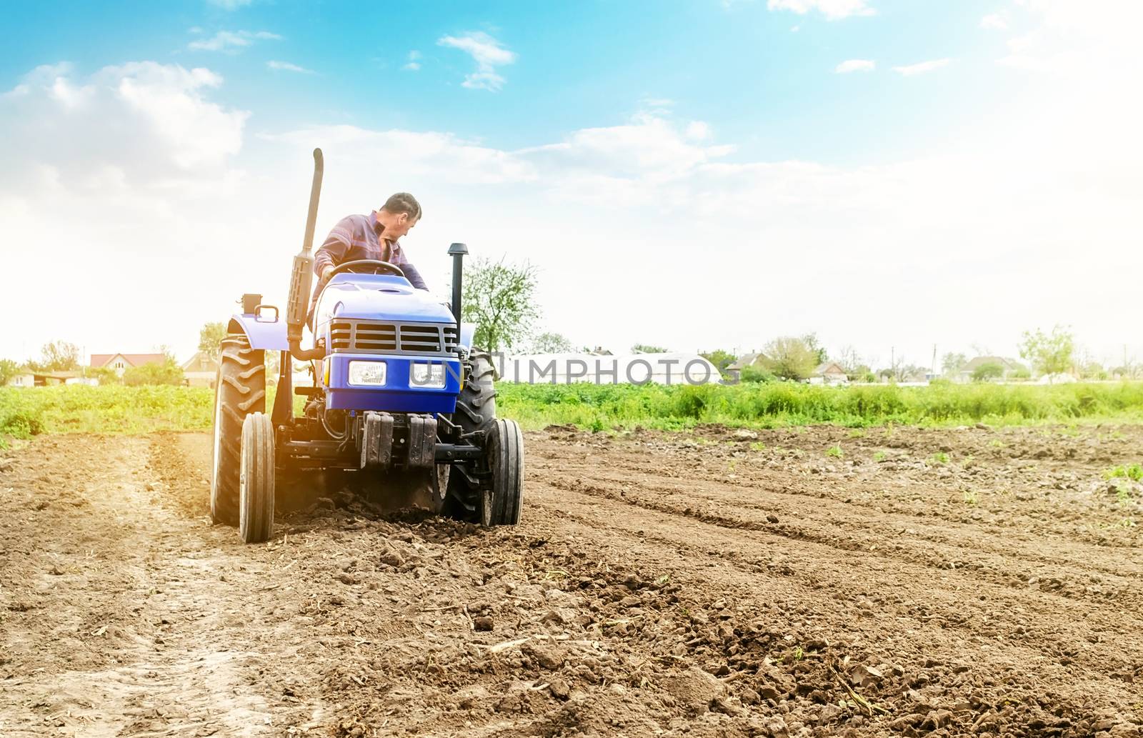 Farmer is processing soil on a tractor. Soil milling, crumbling mixing. Loosening surface, cultivating land for further planting. Agriculture, growing organic food vegetables. Agroindustry, farming. by iLixe48