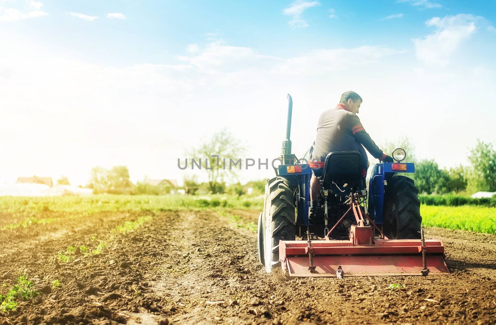 Farmer on a tractor with milling machine loosens, grinds and mixes soil. Cultivation technology equipment. Loosening the surface, cultivating the land for further planting. Farming and agriculture.