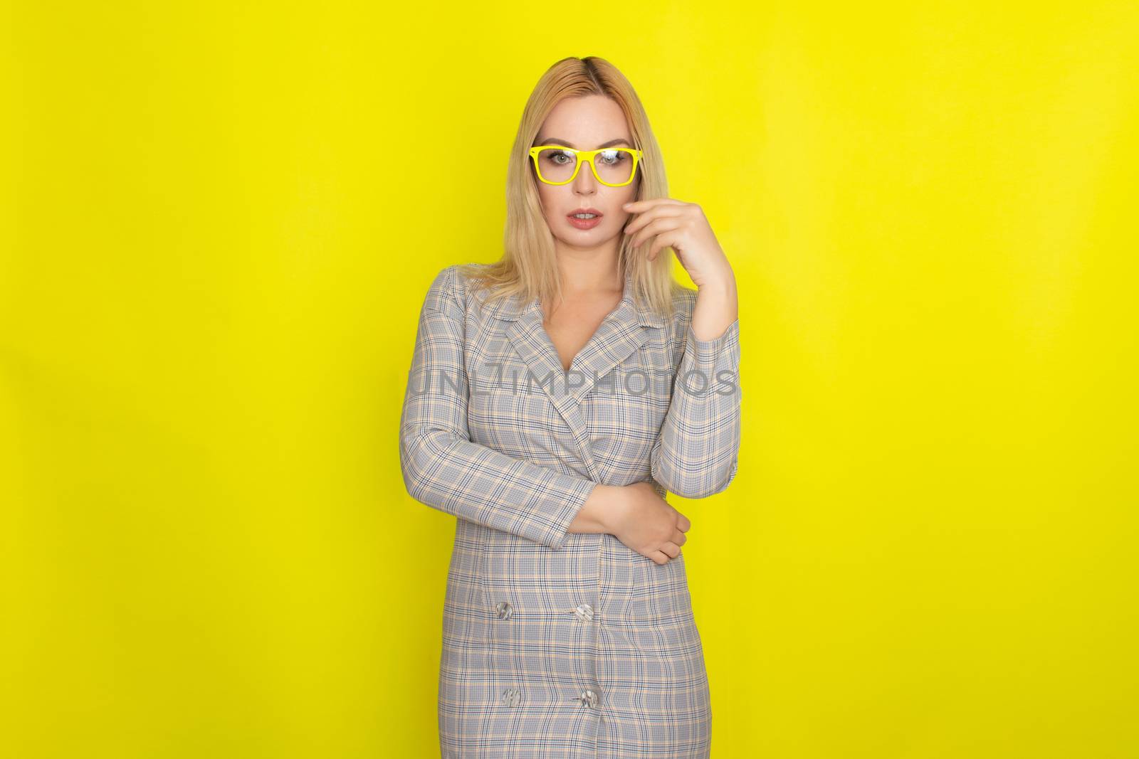 Attractive blonde woman in plaid jacket dress over yellow background by Bonda