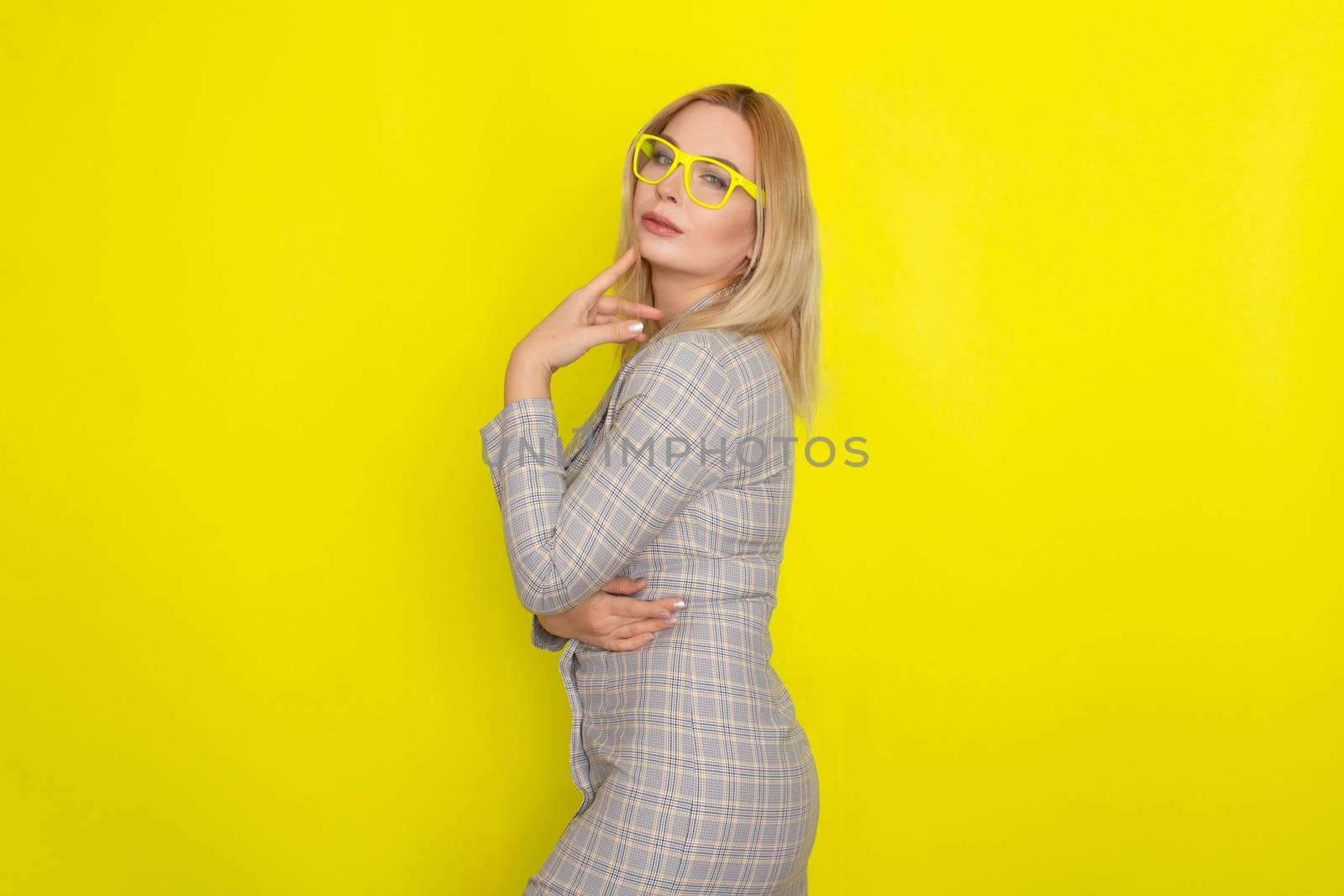 Attractive blonde woman in plaid jacket dress over yellow background by Bonda