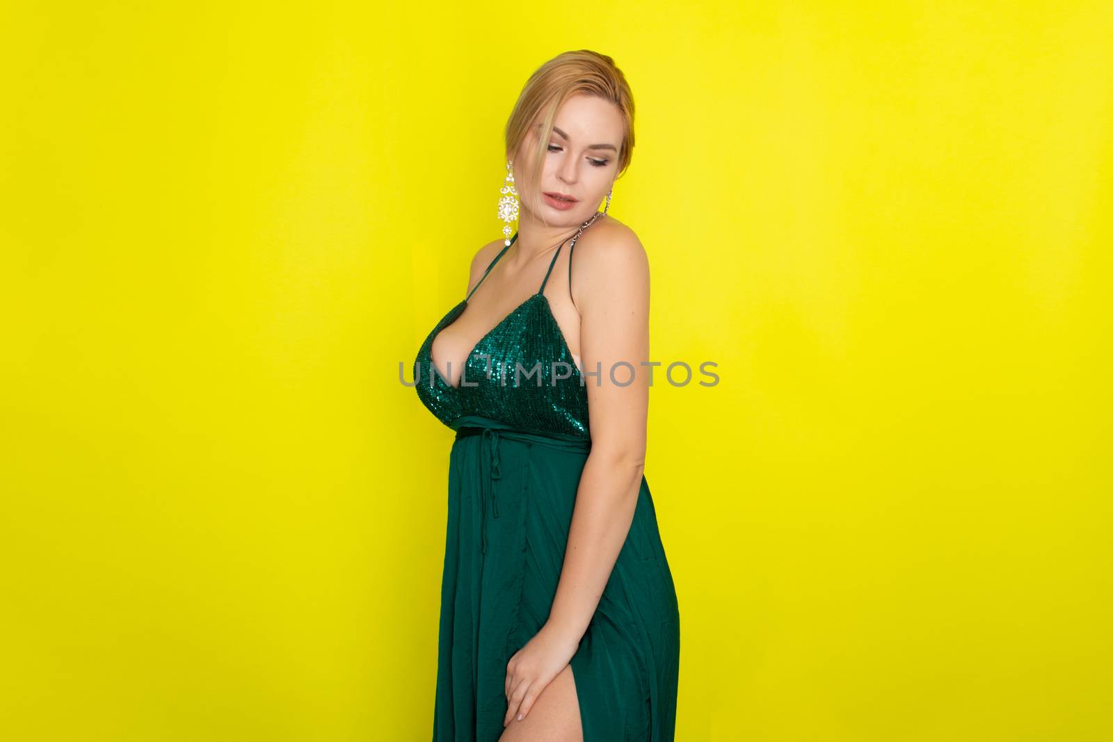 Fashion picture of beautiful young blonde woman wearing green evening dress. Elegant woman ready fo evening