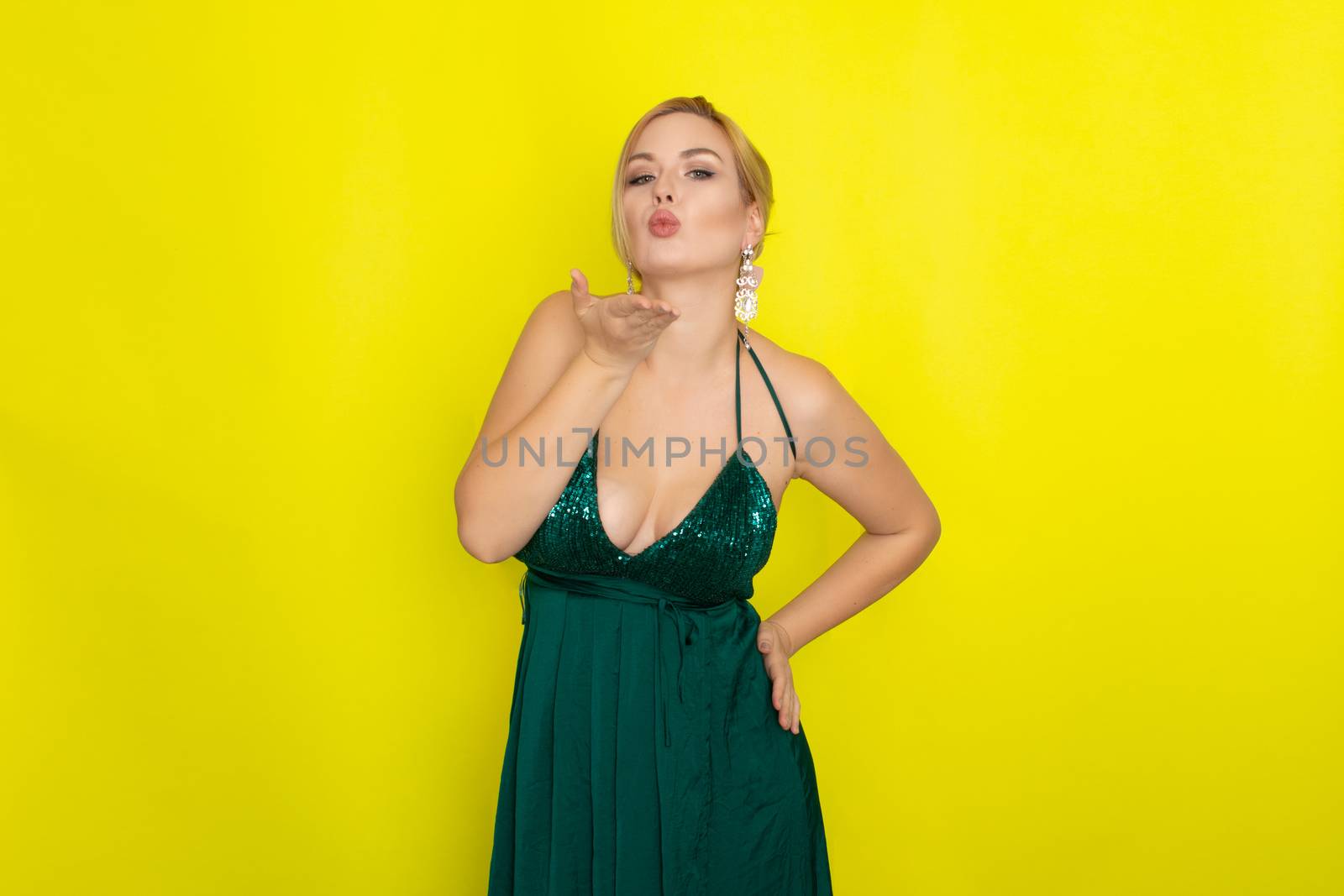 Fashion picture of beautiful young blonde woman wearing green evening dress. Elegant woman ready fo evening