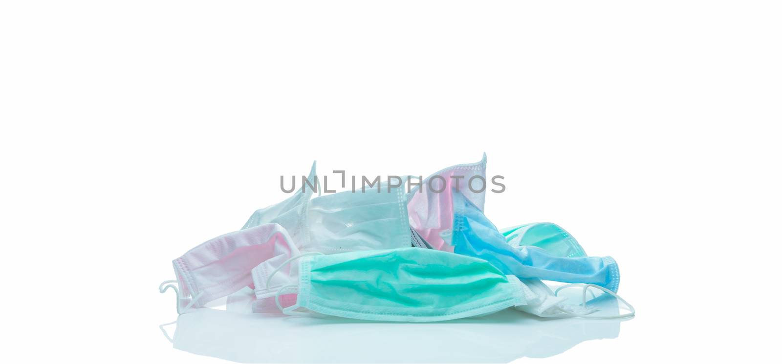 Pile of used surgical face mask isolated on white background. Medical waste. Infectious waste from coronavirus crisis. Pink, green, blue, and white medical face mask waiting for disposal with hygienic