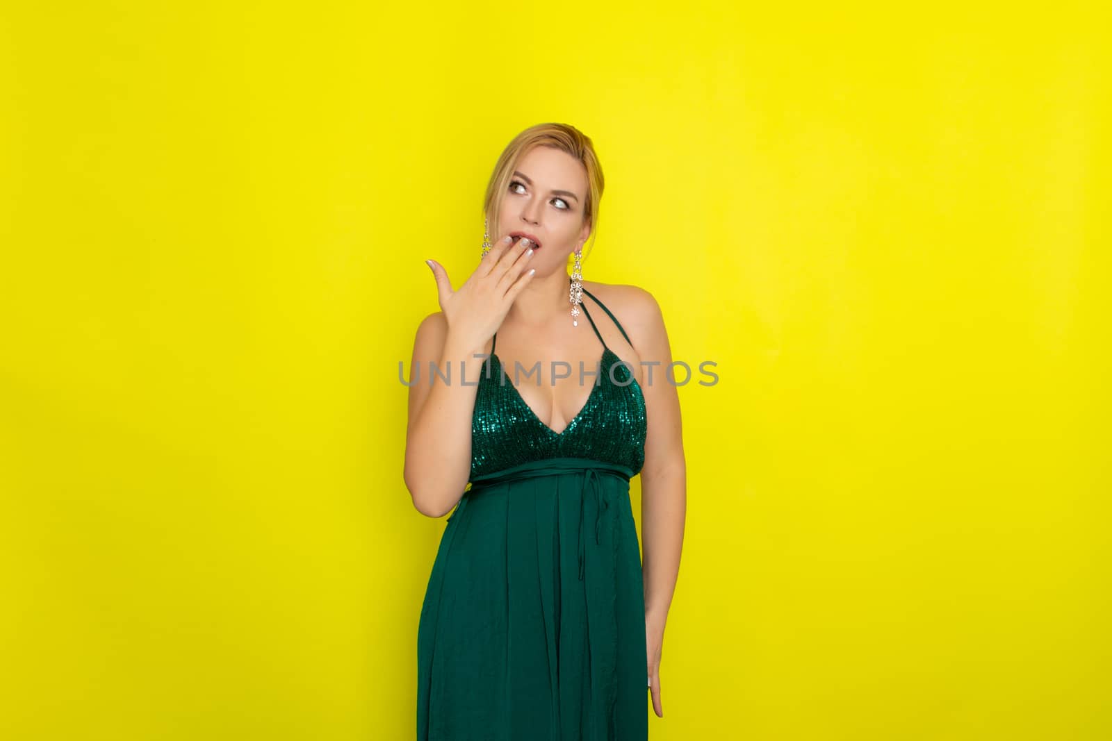 Fashion picture of beautiful young blonde woman wearing green evening dress. Elegant woman ready fo evening