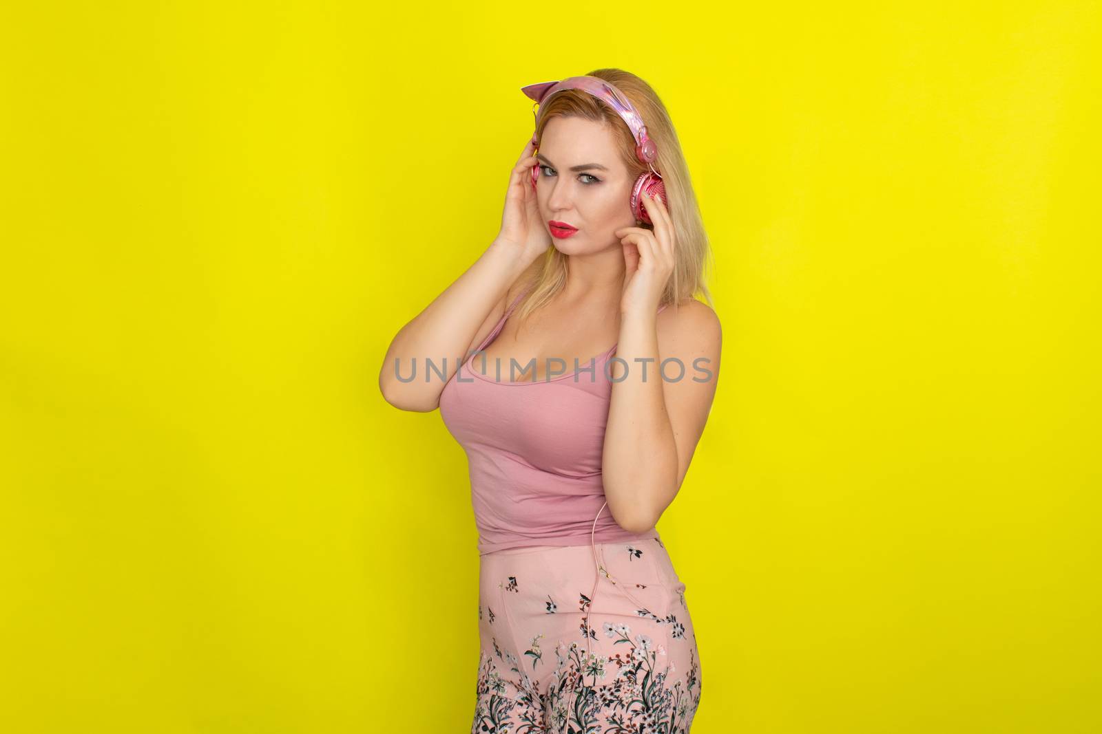 Blonde woman in pink summer clothing wearing pink headphones like kitten ears