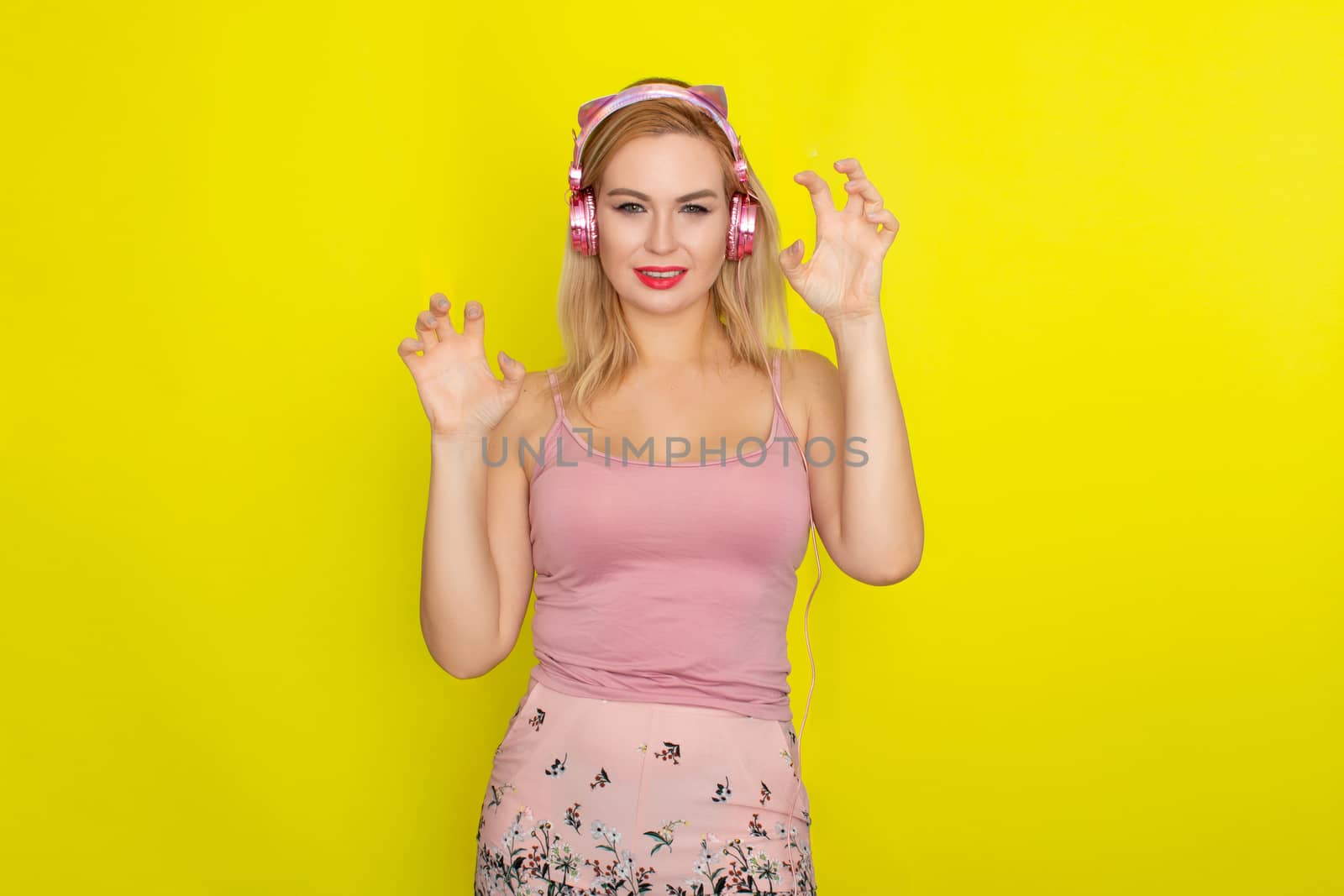 Blonde woman in pink summer clothing wearing pink headphones like kitten ears