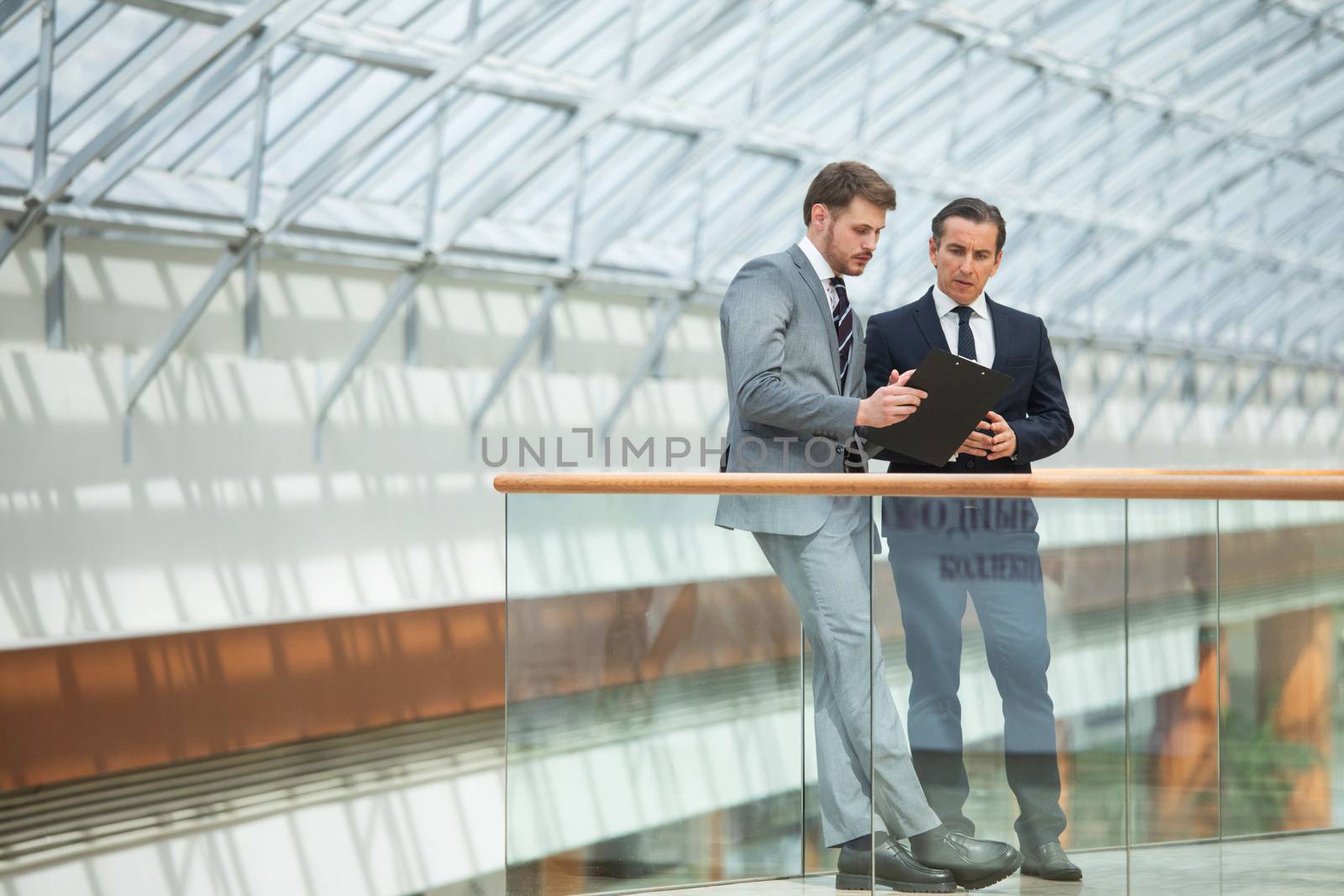 Two business people having informal meeting in modern office discussing documents