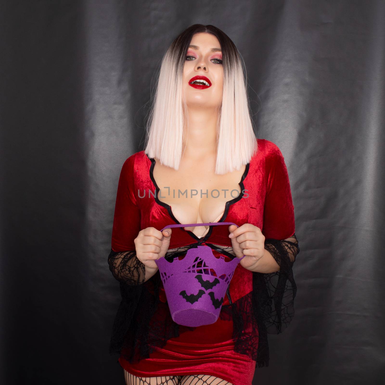 Blonde woman in red vampire dress holding purple bag with bats for sweets by Bonda