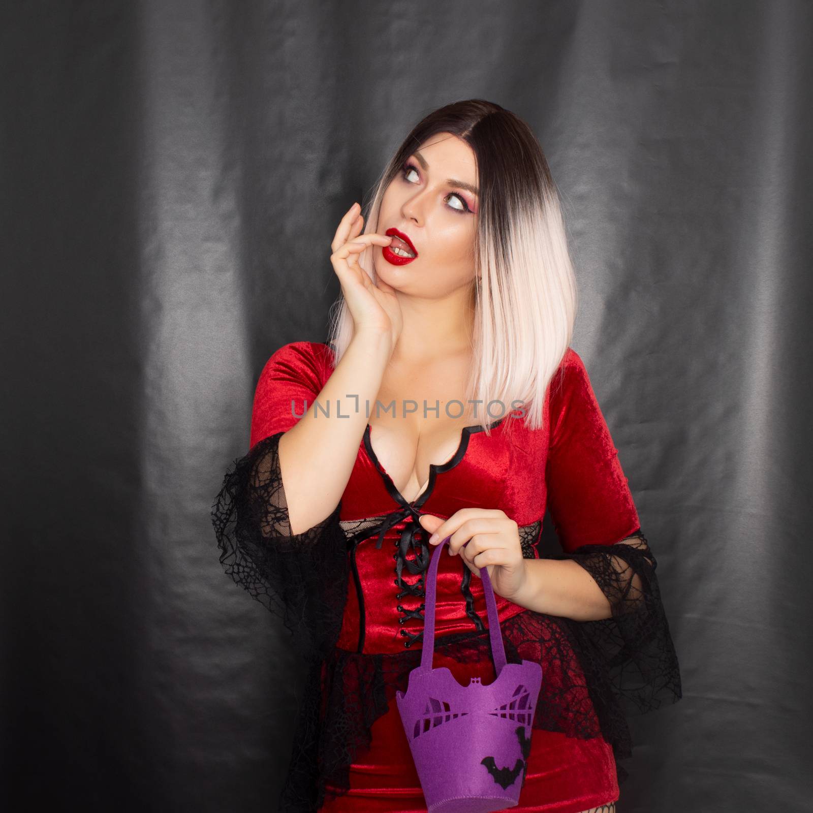 Blonde woman in red vampire dress holding purple bag with bats for sweets by Bonda