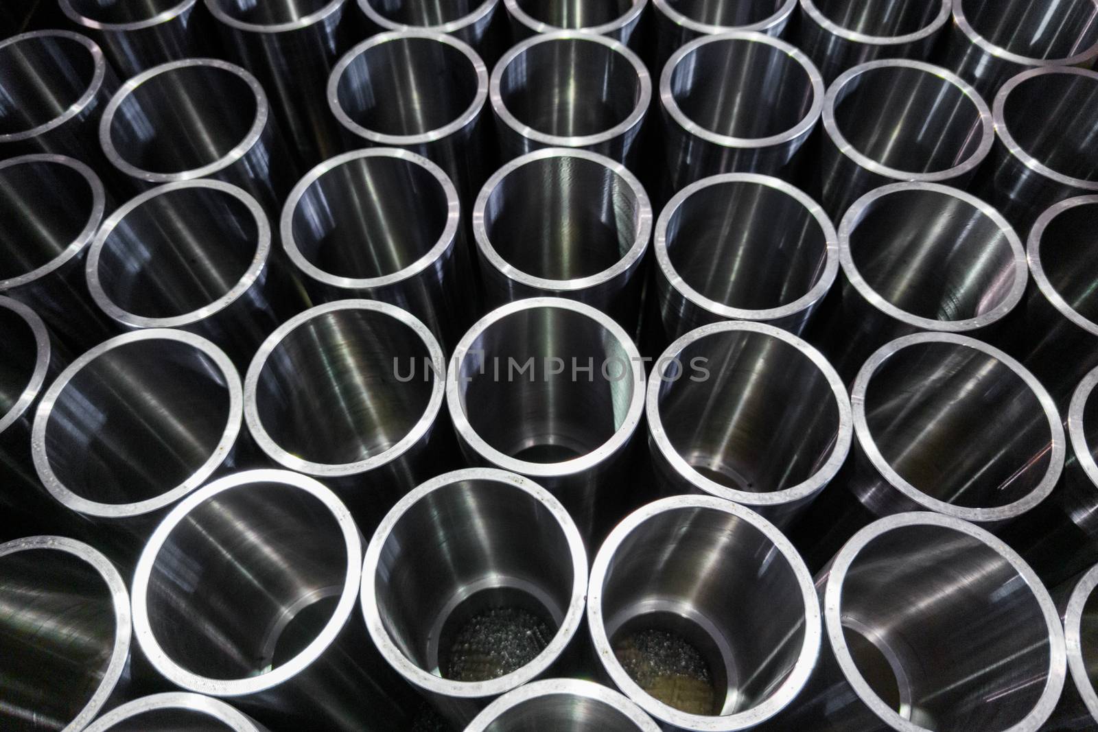 dark industrial background with cnc machined shiny steel pipes - selective focus and lens blur technique