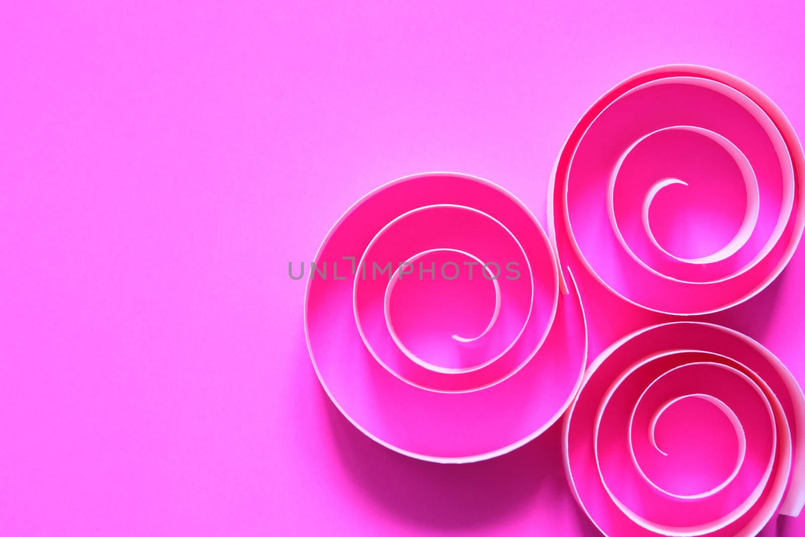 Three purple spiral made from paper on pink background