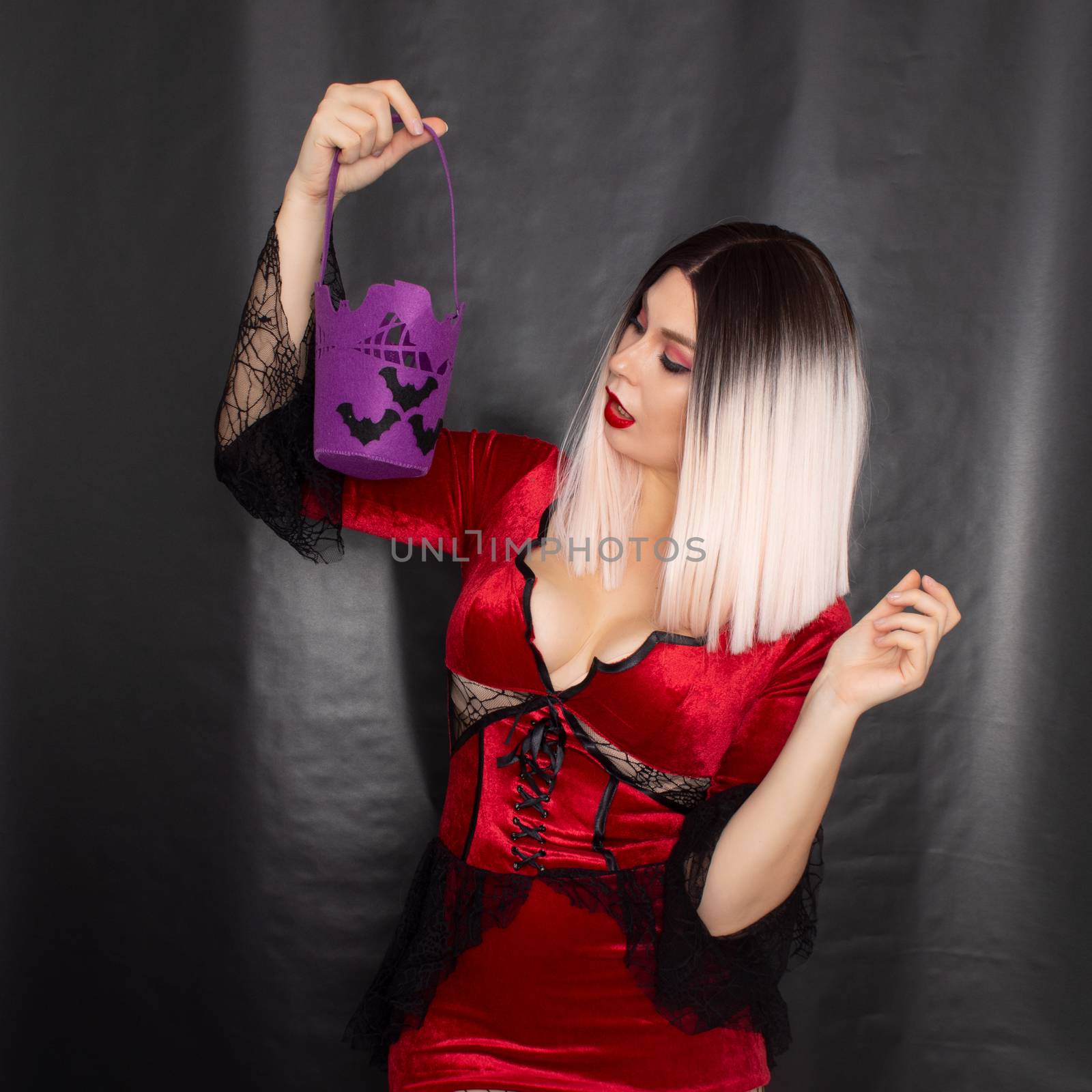 Blonde woman in red vampire dress holding purple bag with bats for sweets by Bonda