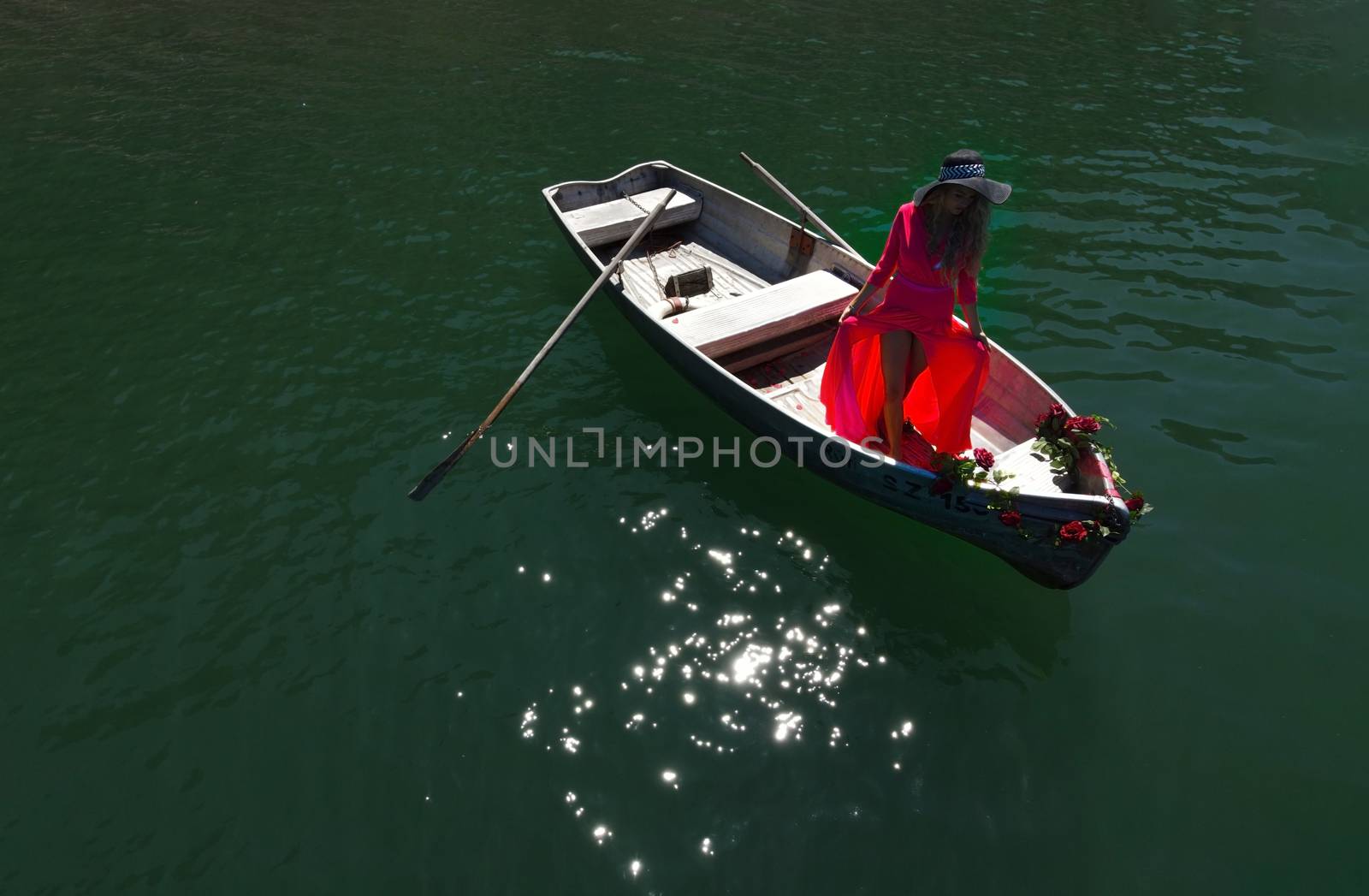 woman with long blond hair on boat on a blue lake by PeterHofstetter