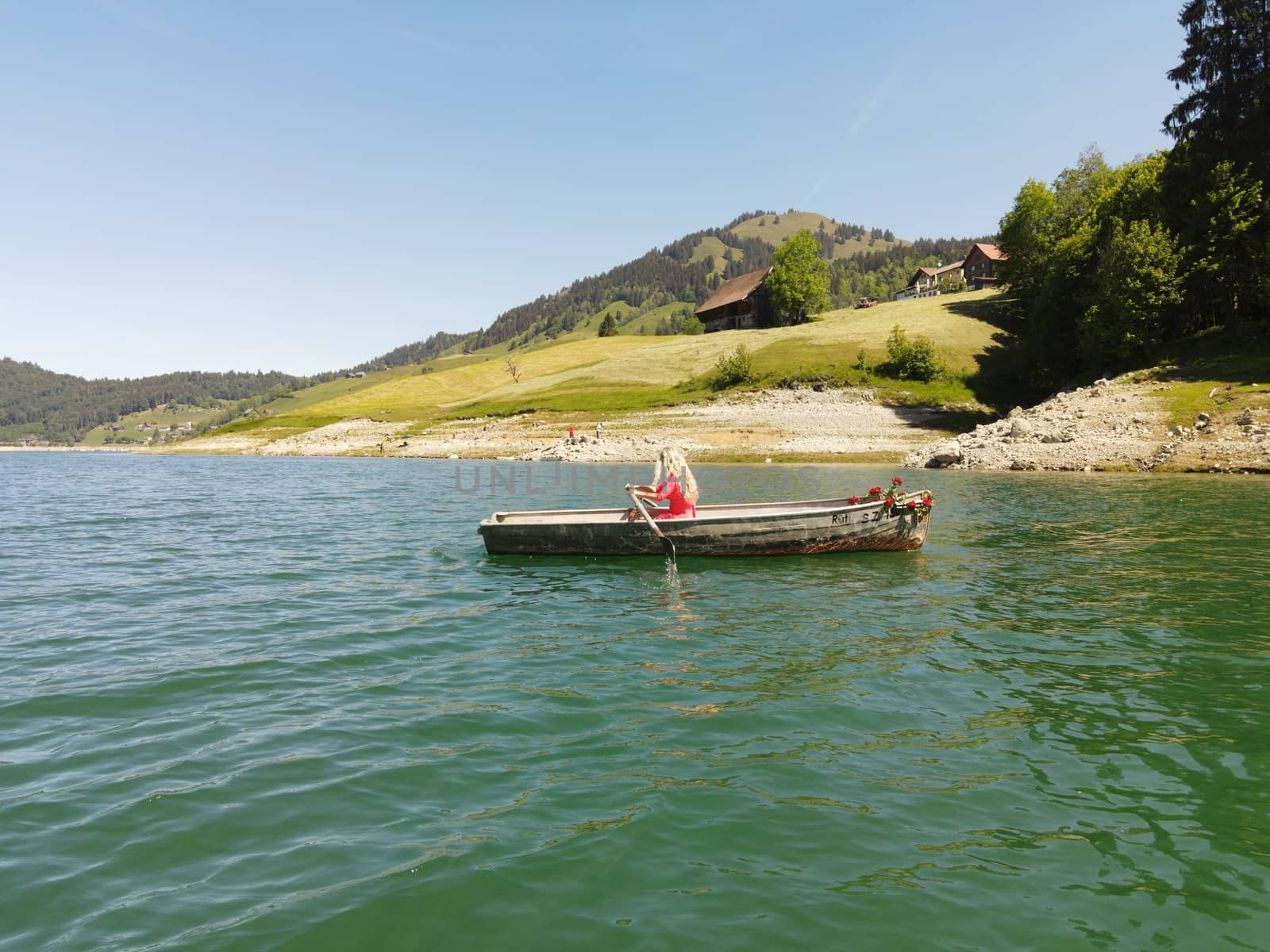 woman with long blond hair on boat with roses and flowers on blue lake