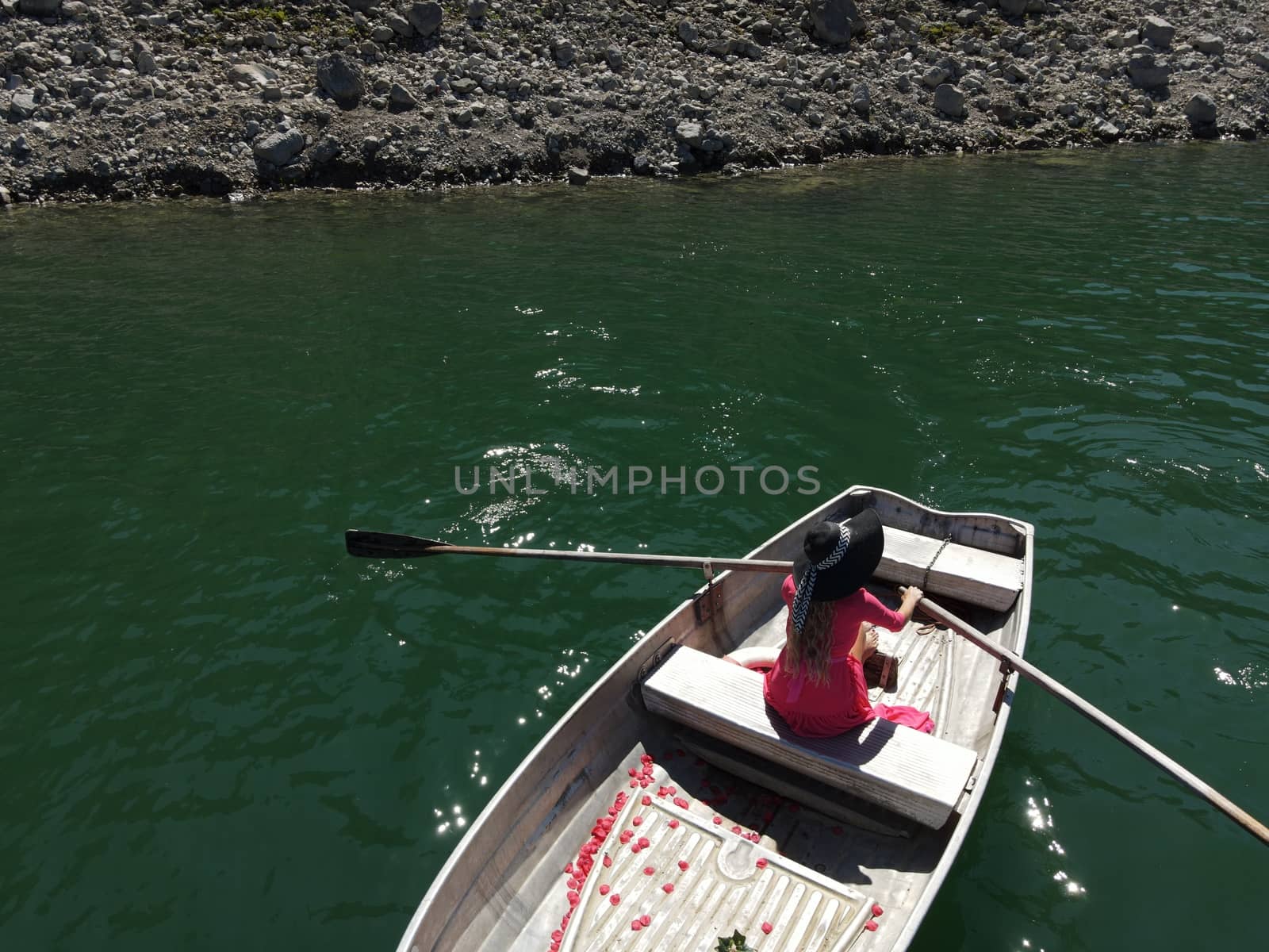 woman with long blond hair on boat with roses and flowers on blue lake