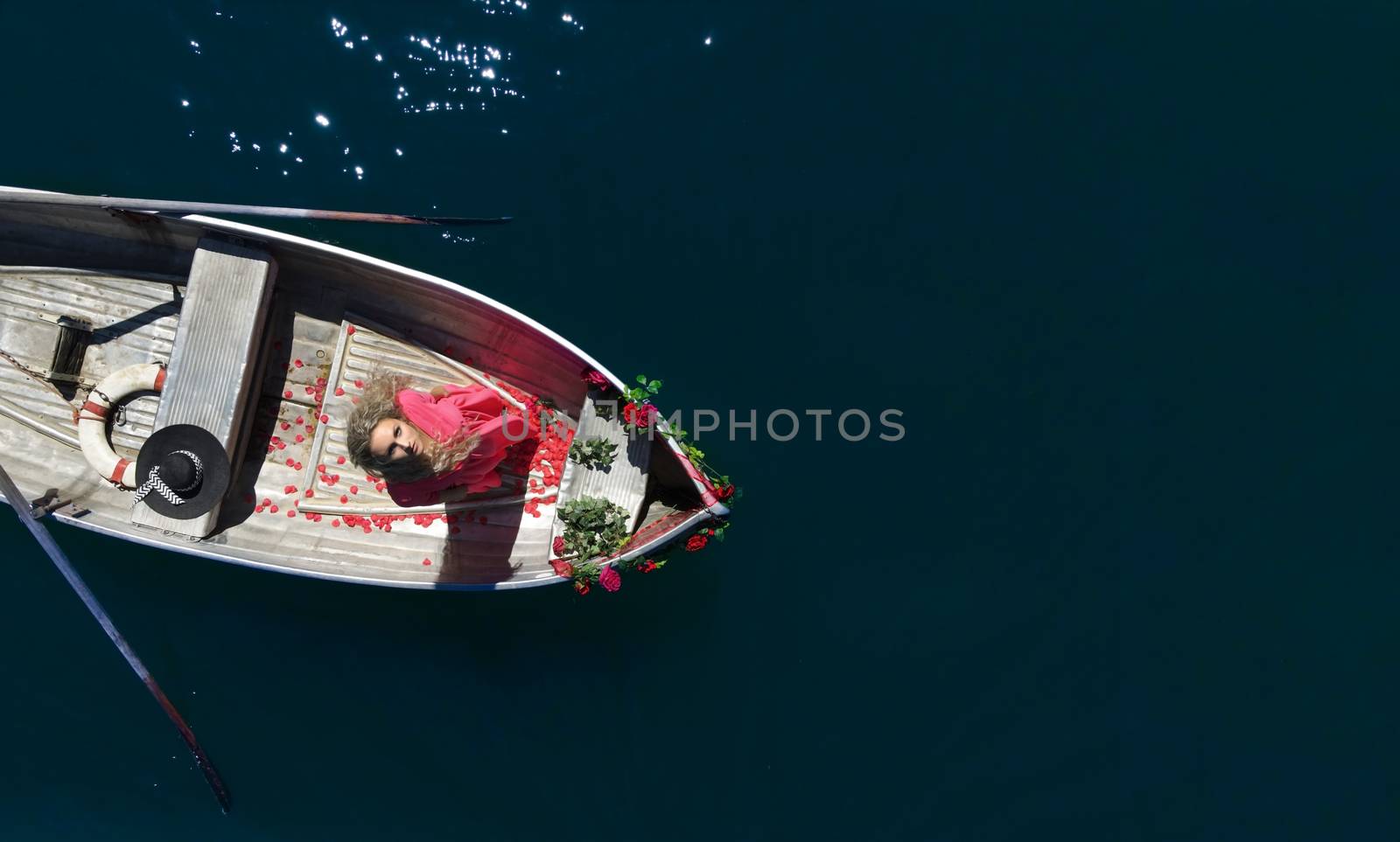 woman with long blond hair on boat on a blue lake by PeterHofstetter