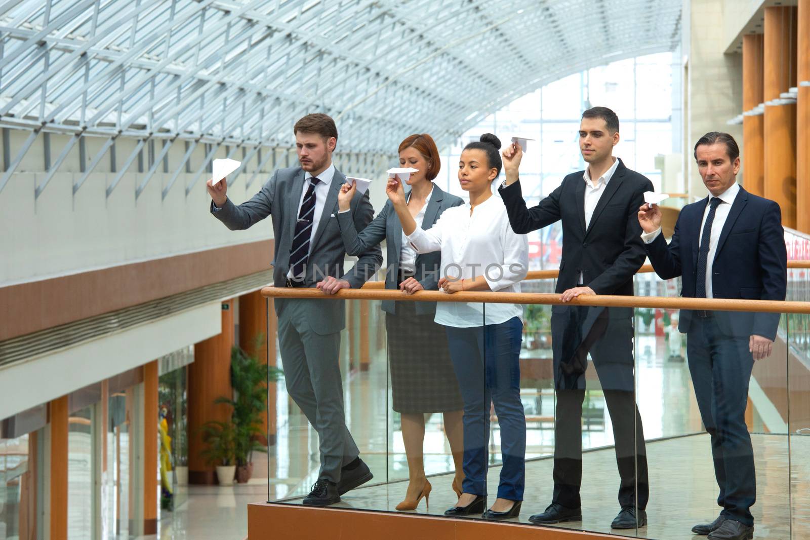 Team of business people throwing together paper planes in modern office building