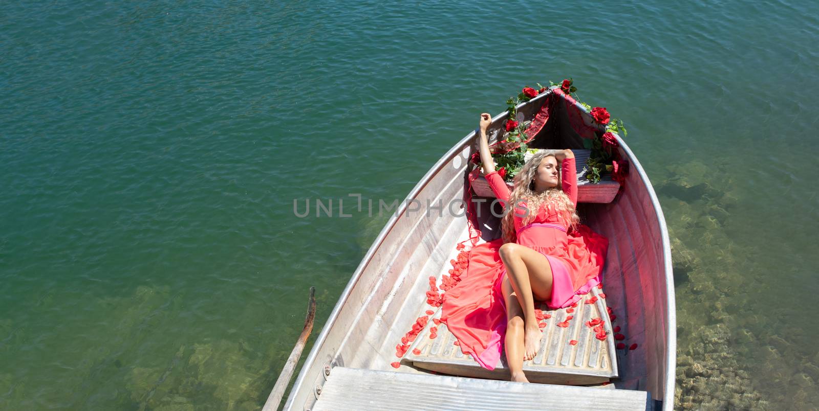 woman with long blond hair on boat on a blue lake by PeterHofstetter