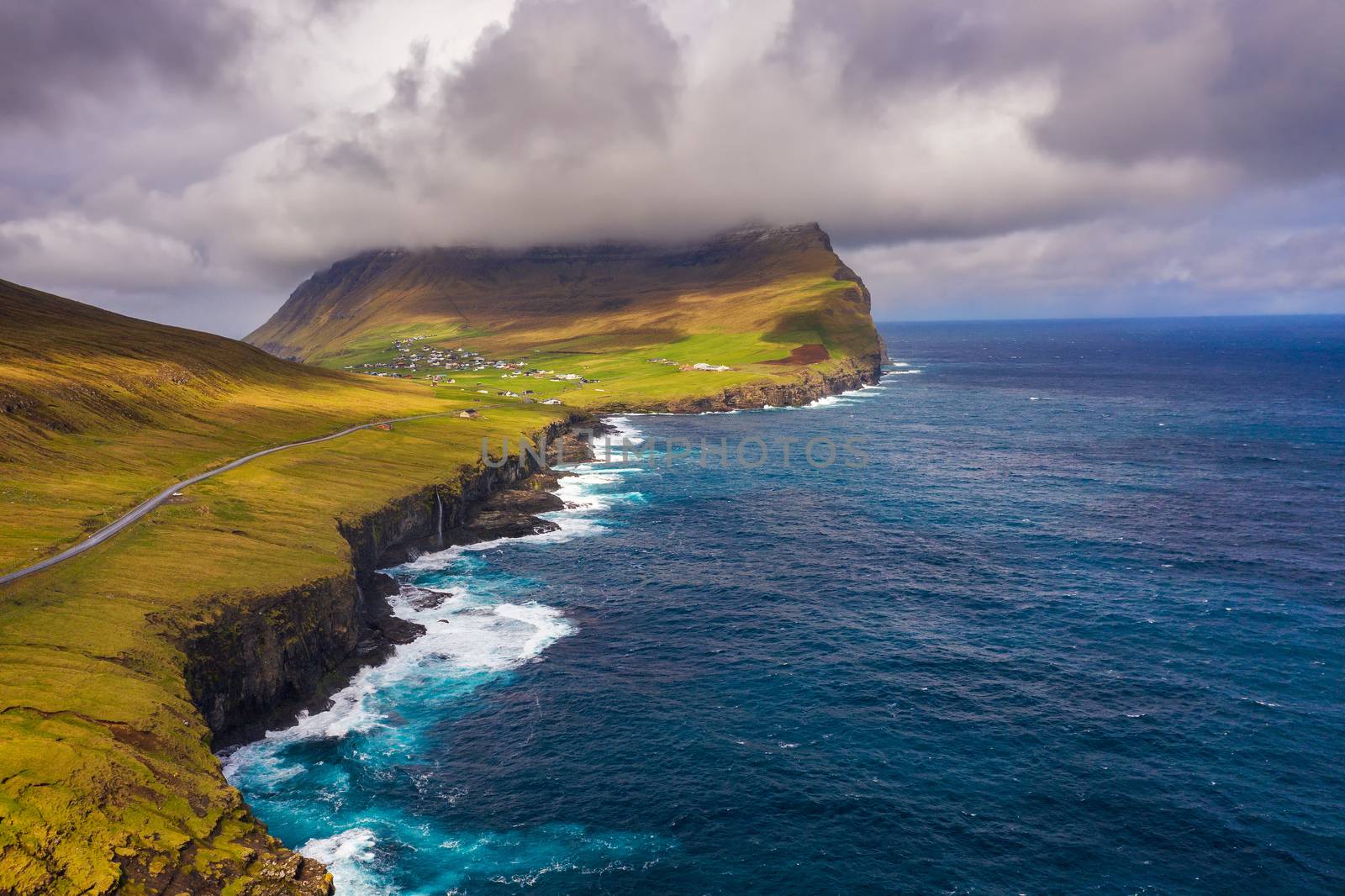 Aerial view of a road going along the atlantic coast to the village of Vidareidi on Faroe Islands surrounded by beatiful scenery.