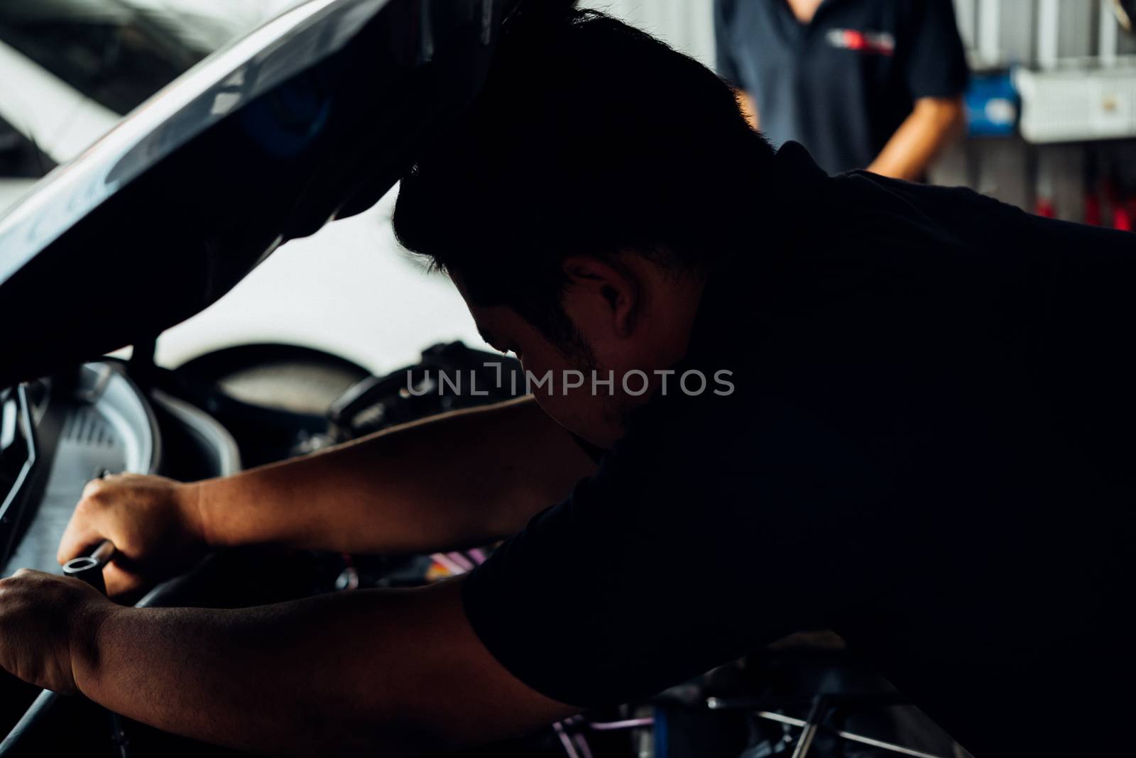 Car mechanic or serviceman checking a car engine for fix and repair problem at car garage or repair shop