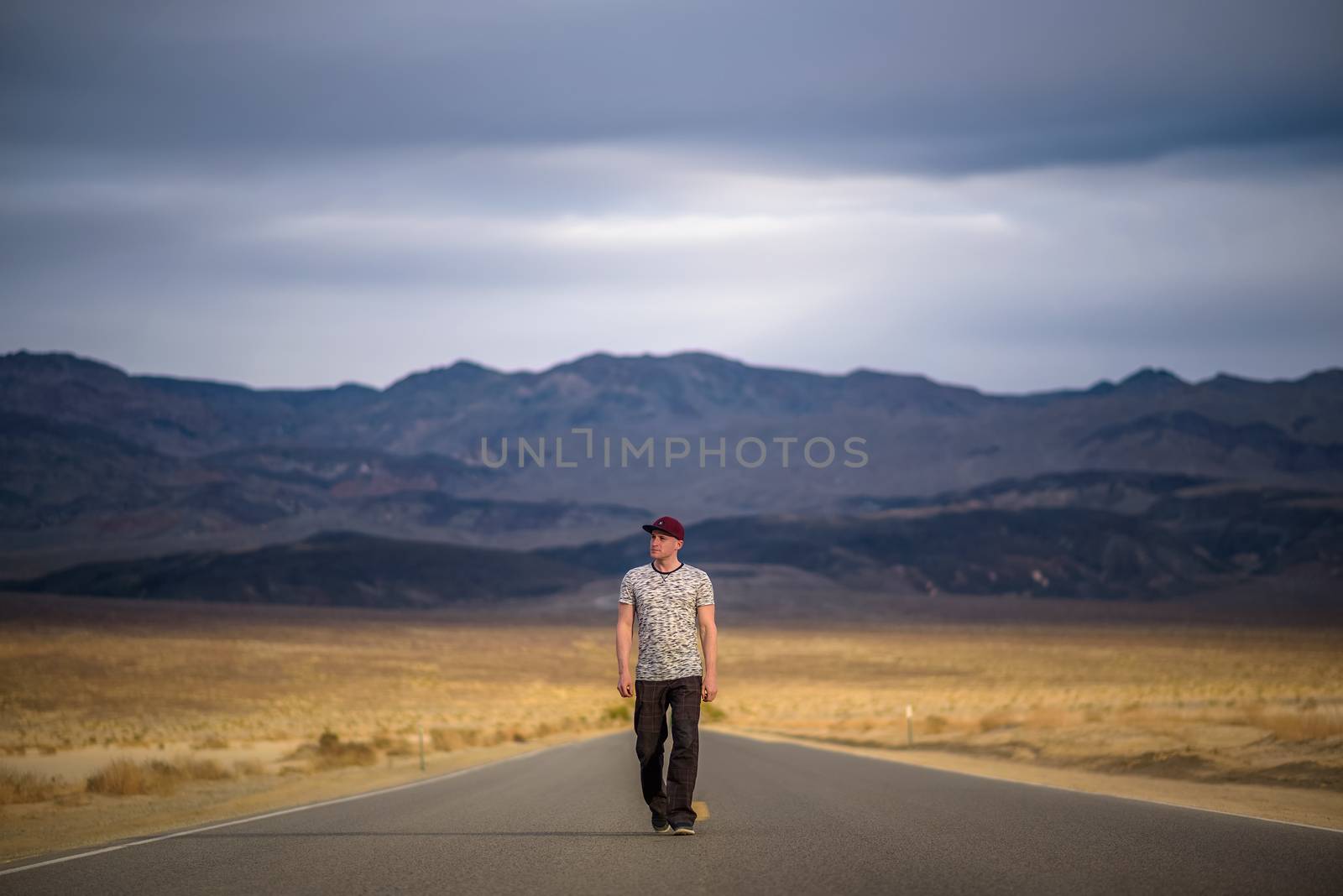 Young man walking alone through an empty street in the desert of Death Valley by nickfox