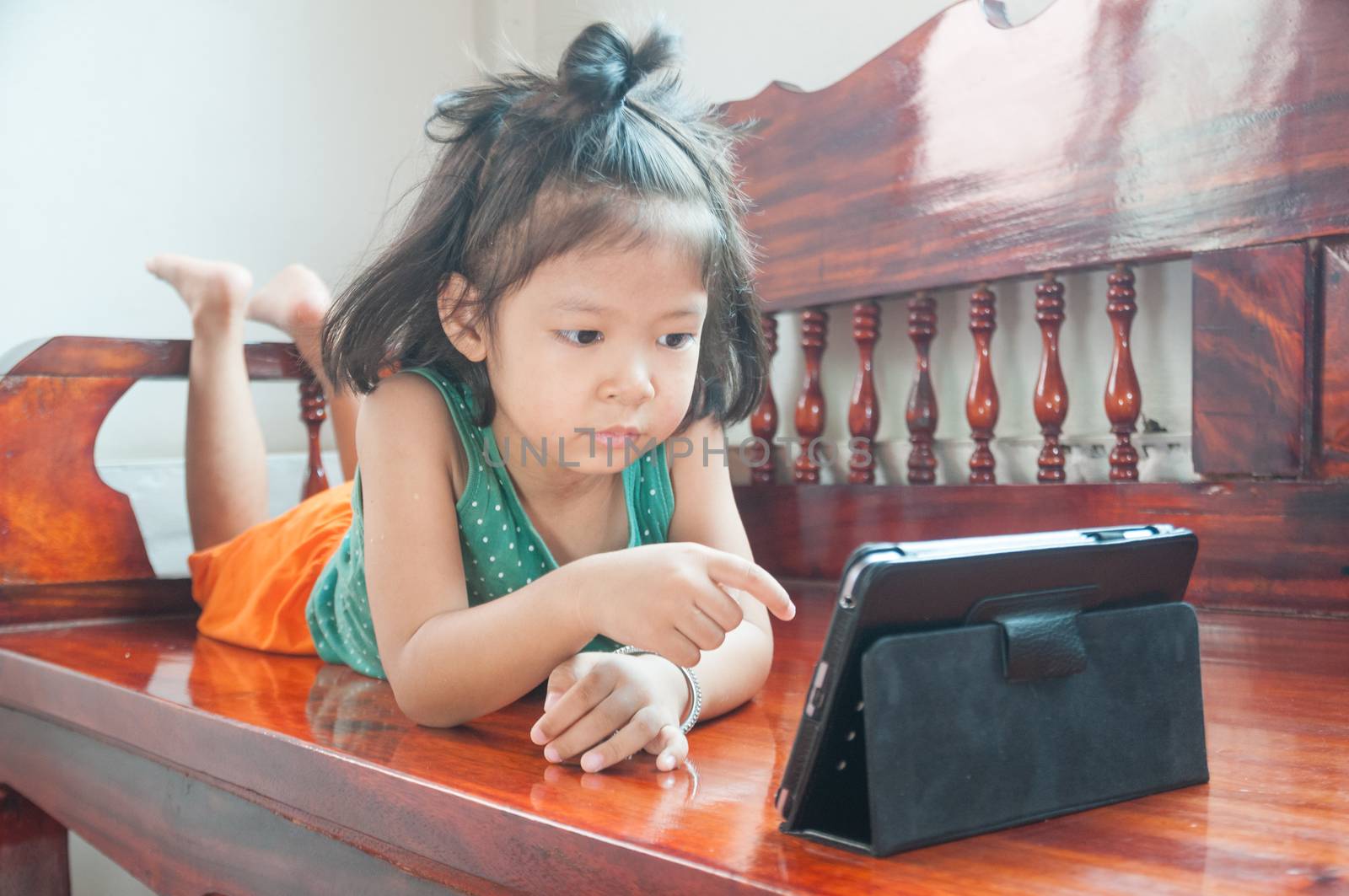 Young Girl lying on wooden stool and Learning online course on W by thampapon