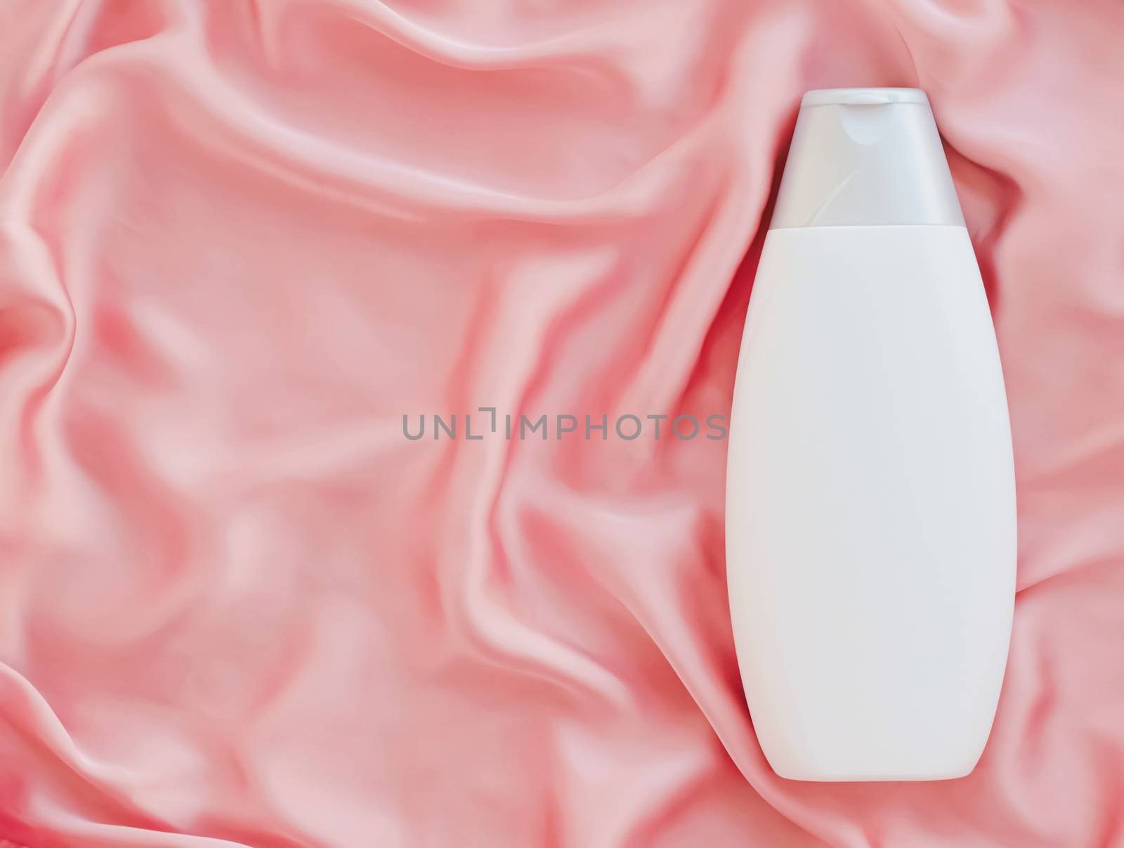 Blank label cosmetic container bottle as product mockup on pink silk background by Anneleven