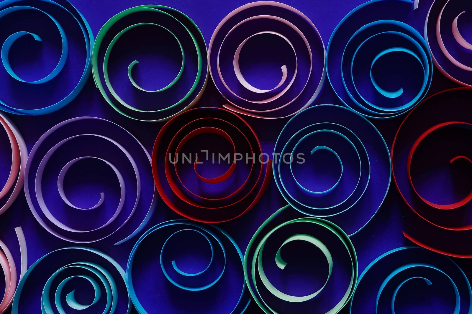 Multicolored spirals made from paper on blue background