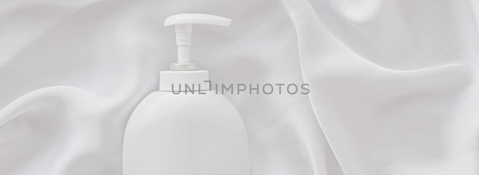 Blank label cosmetic container bottle as product mockup on white silk background by Anneleven